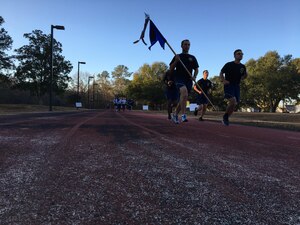 2nd Lt. Brett Betit, 628th Civil Engineer Squadron (CES) programmer, runs with the 628th CES guidon during the Wingman Day Olympics here, Jan. 13. For Wingman Day Airmen participated in various events with their squadrons to foster teamwork and communication while covering the four domains of Comprehensive Airmen Fitness.
