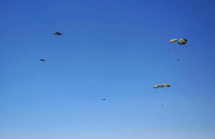 U.S. Air Force C-17 Globemasters drop cargo over a dirt landing strip while flying in support of the Air Force Weapons School over Nellis Air Force Base, Nev., May 23, 2012. The Air Force Weapons School is a five-and-a-half-month training course which provides selected officers with the most advanced training in weapons and tactics employment. Throughout the course, students receive an average of 400 hours of post graduate-level academics and participate in demanding combat training missions.