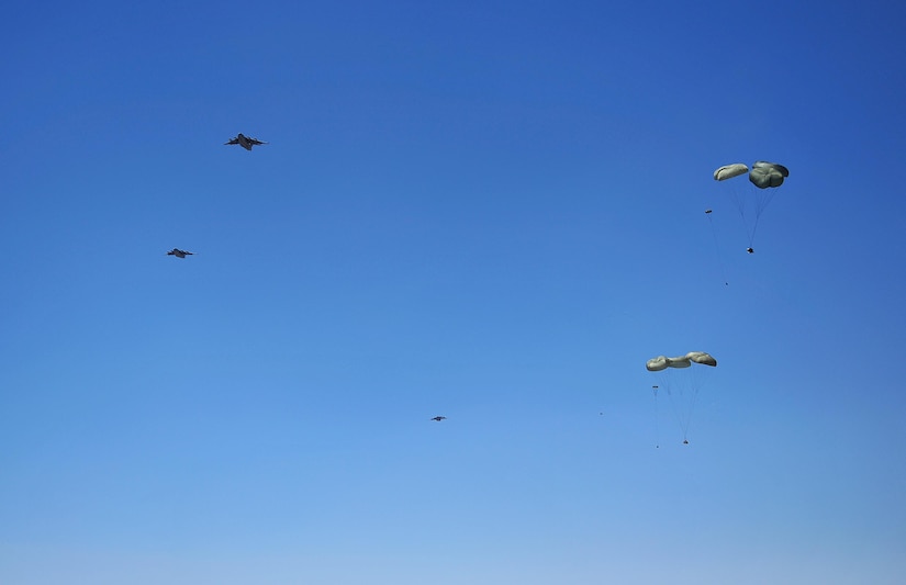 U.S. Air Force C-17 Globemasters drop cargo over a dirt landing strip while flying in support of the Air Force Weapons School over Nellis Air Force Base, Nev., May 23, 2012. The Air Force Weapons School is a five-and-a-half-month training course which provides selected officers with the most advanced training in weapons and tactics employment. Throughout the course, students receive an average of 400 hours of post graduate-level academics and participate in demanding combat training missions.