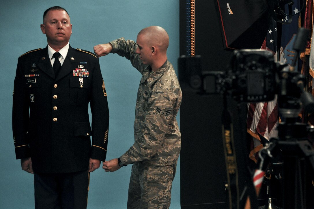 U.S. Air Force Airman 1st Class Randall Moose, 17th Training Wing Public Affairs photojournalist, adjusts the uniform of U.S. Army Sgt. 1st Class Corey Whigham, 344th military intelligence battalion, before taking an official photo in the public affairs building on Goodfellow Air Force Base, Texas, January 12, 2016. The Public Affairs office takes official photos for all services on Goodfellow. (U.S. Air Force photo by 2nd Lt. Tisha Wilkerson/Released)