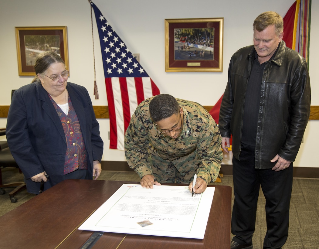 Colonel Sekou S. Karega, commanding officer, commanding officer of Marine Corps Logistics Base Barstow, signs a proclamation designating the week of Feb. 27 - March 4, 2017 Military Saves Week. Standing by are Lynda Schmidt, Personal Finance Managment Program Specialist, and Patrick Rewerts, Career Resource Center Manager, Marine Corps Community Services, MCLB Barstow.