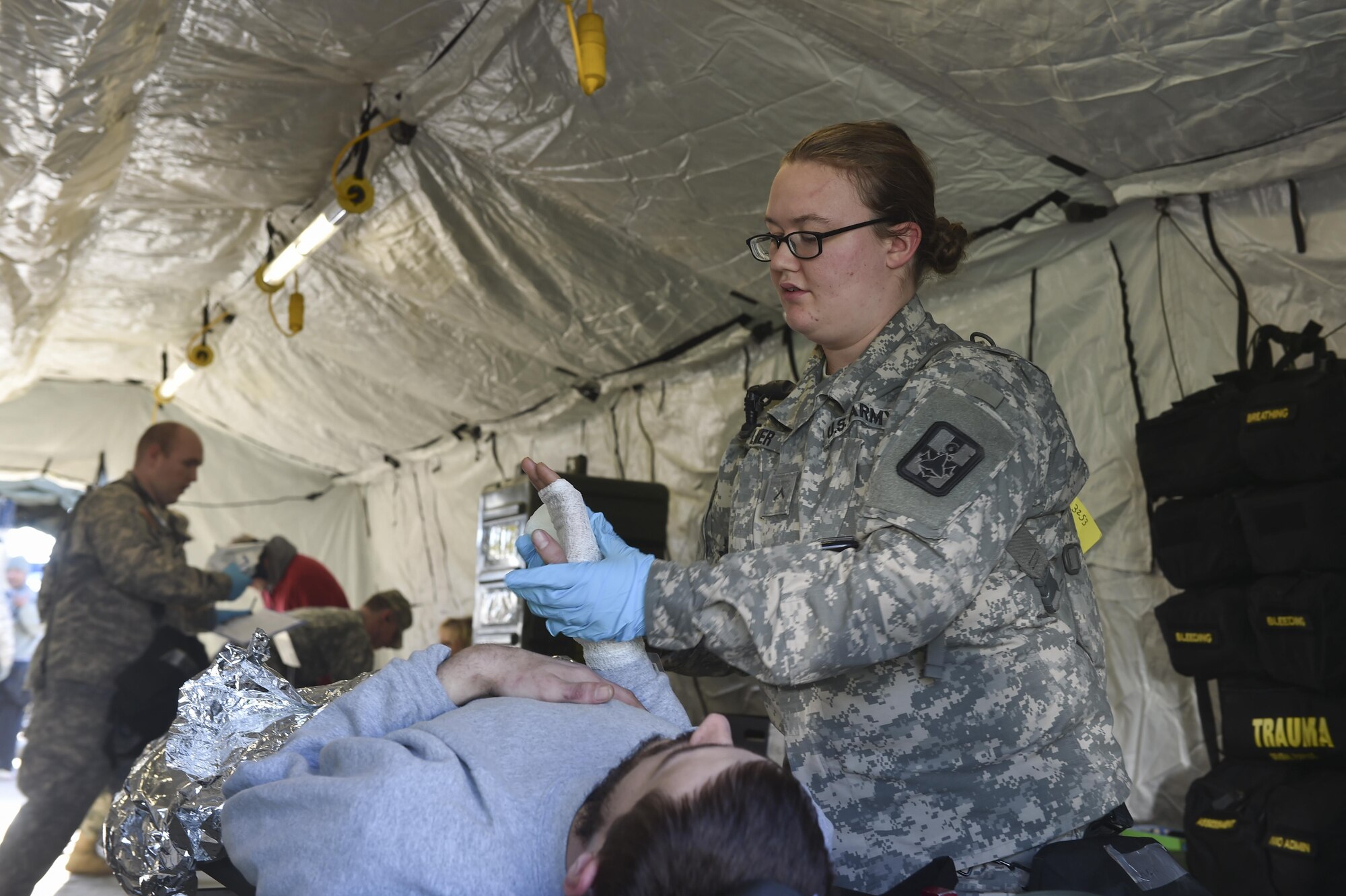 U.S. Army Pfc. Elizabeth Zellmer, 409th Area Support Medical Company medical technician, applies bandages to a simulated patient’s hand during a mass casualty and decontamination exercise at North Auxiliary Airfield in North, South Carolina Jan. 10, 2017. The temporary treatment facilities allow for the 414th Chemical, Biological, Radiological and Nuclear Company and 409th ASMC to work together to triage patients, decontaminate them and provide medical care quickly. North Auxiliary Airfield is a Joint Base Charleston asset capable of hosting a wide range of exercises.