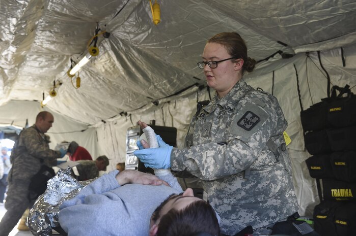 U.S. Army Pfc. Elizabeth Zellmer, 409th Area Support Medical Company medical technician, applies bandages to a simulated patient’s hand during a mass casualty and decontamination exercise at North Auxiliary Airfield in North, South Carolina Jan. 10, 2017. The temporary treatment facilities allow for the 414th Chemical, Biological, Radiological and Nuclear Company and 409th ASMC to work together to triage patients, decontaminate them and provide medical care quickly. North Auxiliary Airfield is a Joint Base Charleston asset capable of hosting a wide range of exercises.