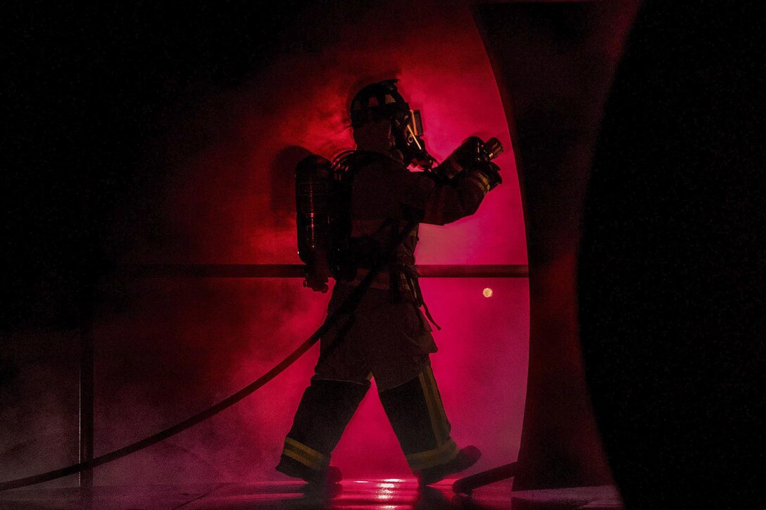 An airman enters a prop aircraft at nighttime during training to fight fires at Moody Air Force Base, Ga., Jan. 10, 2017. The airman is a firefighter assigned to the 23rd Civil Engineer Squadron. After extinguishing external fires, firefighters entered the prop aircraft to continue combating the flames inside. Air Force photo by Airman 1st Class Daniel Snider