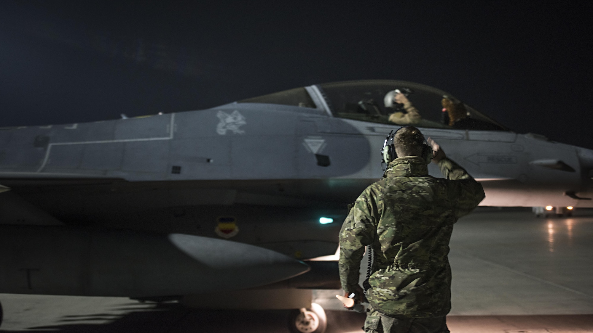 Capt. David, 79th Expeditionary Fighter Squadron pilot, and Staff Sgt. Daniel Lasal, 455th Expeditionary Aircraft Maintenance Squadron dedicated crew chief, salute one another before a night mission Jan. 13, 2017 at Bagram Airfield, Afghanistan. David enlisted in the Air Force in 2004 as an F-16 Fighting Falcon avionics specialist and now flies the same airframe he used to be a maintainer for. (U.S. Air Force photo by Staff Sgt. Katherine Spessa)