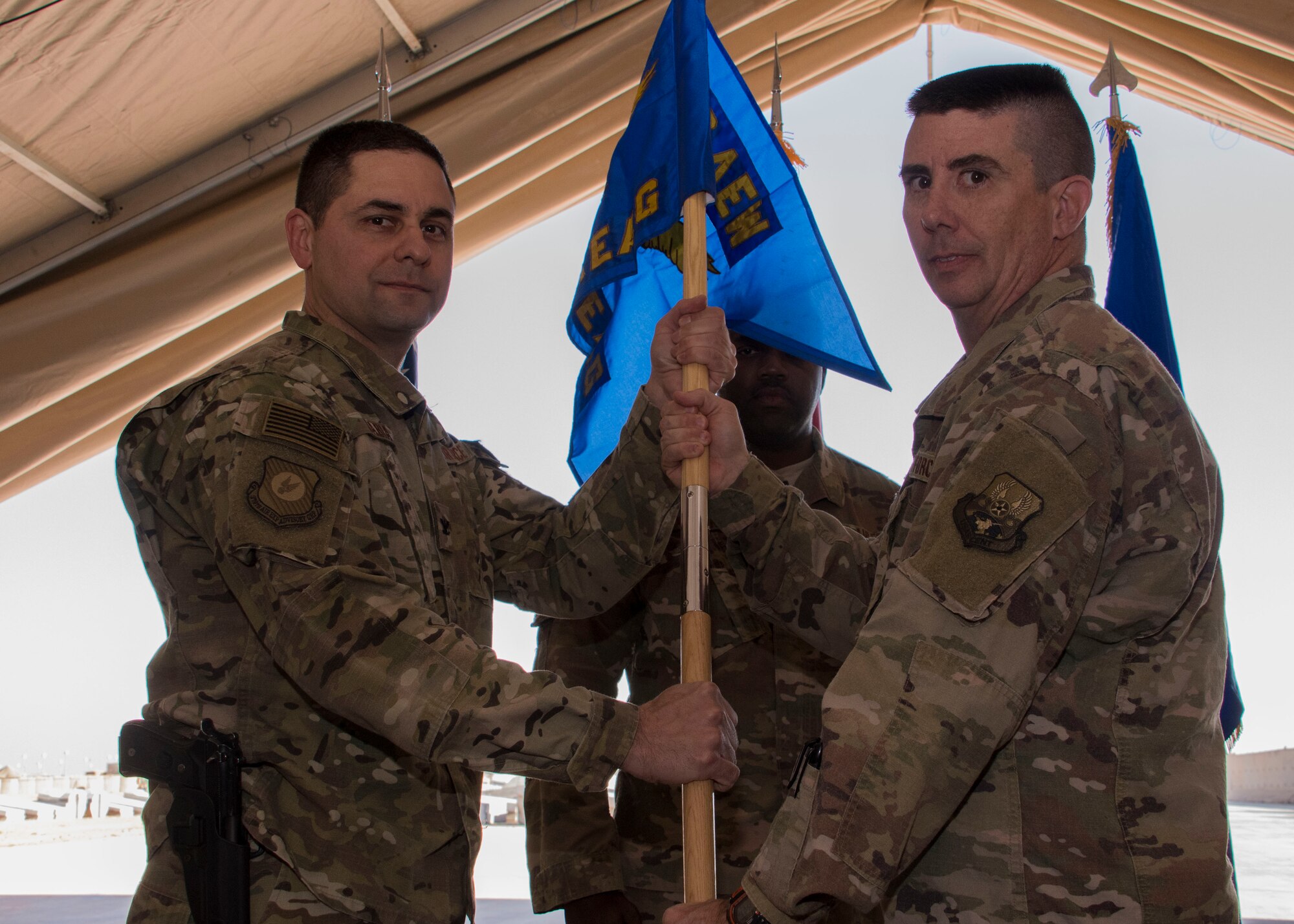 U.S. Air Force Col. Jay Sabia, 370th Air Expeditionary Advisory Group commander, left, receives the group flag from U.S. Air Force Lt. Col. Brett Wilkinson, the outgoing 370th AEAG Detachment 1 commander, right, at a change of command ceremony, Jan. 8, 2017 at Al Asad Air Base, Iraq. Possession of the flag symbolizes command over the unit. (U.S. Air Force photo/Senior Airman Andrew Park)