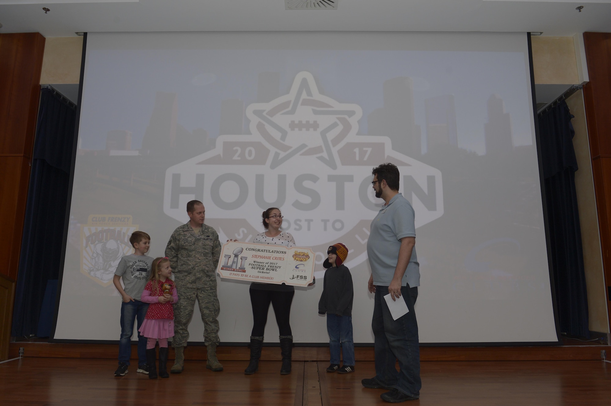 Stephanie Crites, wife of U.S. Air Force Staff Sgt. Richard Crites, 52nd Maintenance Squadron senior munitions inspector, with their three children are presented with the grand prize from the Football Frenzy contest at Club Eifel on Spangdahlem Air Base, Germany, Jan. 10, 2017. The grand prize is two tickets to Super Bowl LI with airfare and hotel. (U.S. Air Force photo by Staff Sgt. Jonathan Snyder)