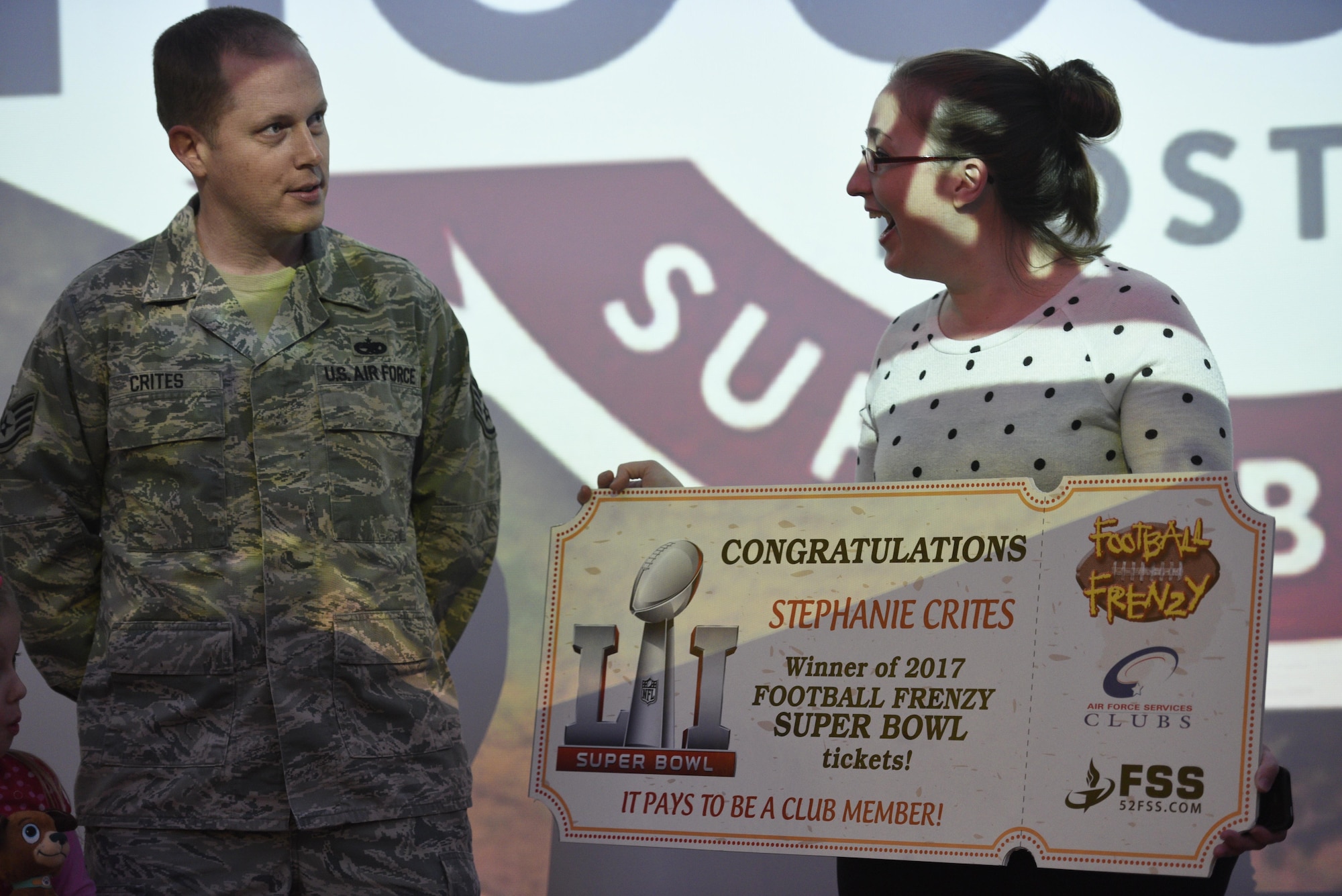 Stephanie Crites, wife of U.S. Air Force Staff Sgt. Richard Crites, left, 52nd Maintenance Squadron senior munitions inspector, is presented with the grand prize from the Football Frenzy contest at Club Eifel on Spangdahlem Air Base, Germany, Jan. 10, 2017. The grand prize is two tickets to Super Bowl LI with airfare and hotel. (U.S. Air Force photo by Staff Sgt. Jonathan Snyder)