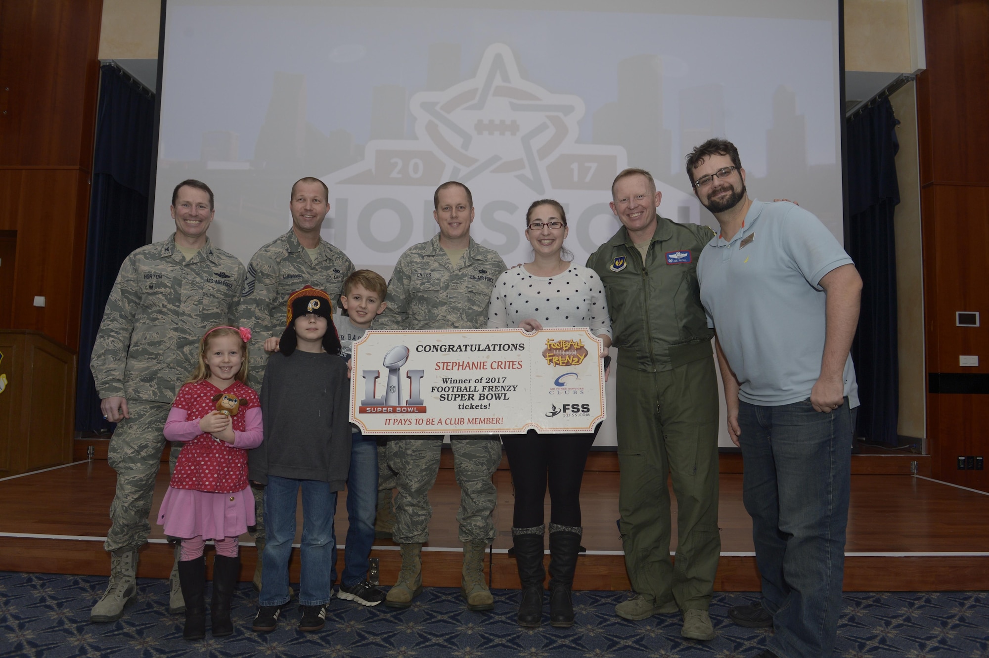 U.S. Air Force Staff Sgt. Richard Crites, 52nd Maintenance Squadron senior munitions inspector, with his family are presented with the grand prize from the Football Frenzy contest by 52nd Fighter Wing leadership and 52nd Force Support Squadron at Club Eifel on Spangdahlem Air Base, Germany, Jan. 10, 2017. The grand prize is two tickets to Super Bowl LI with airfare and hotel. (U.S. Air Force photo
by Staff Sgt. Jonathan Snyder)