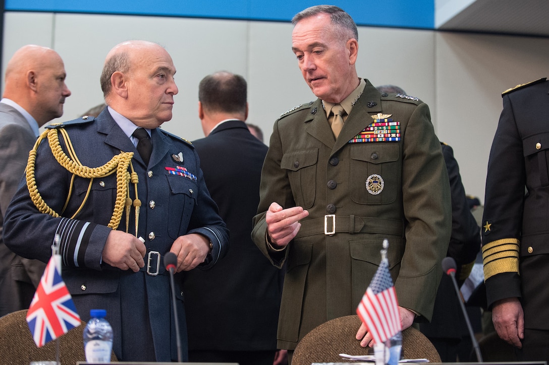 Marine Corps Gen. Joe Dunford, chairman of the Joint Chiefs of Staff, speaks with Air Chief Marshal Sir Stuart Peach, British defense chief, before a NATO meeting.