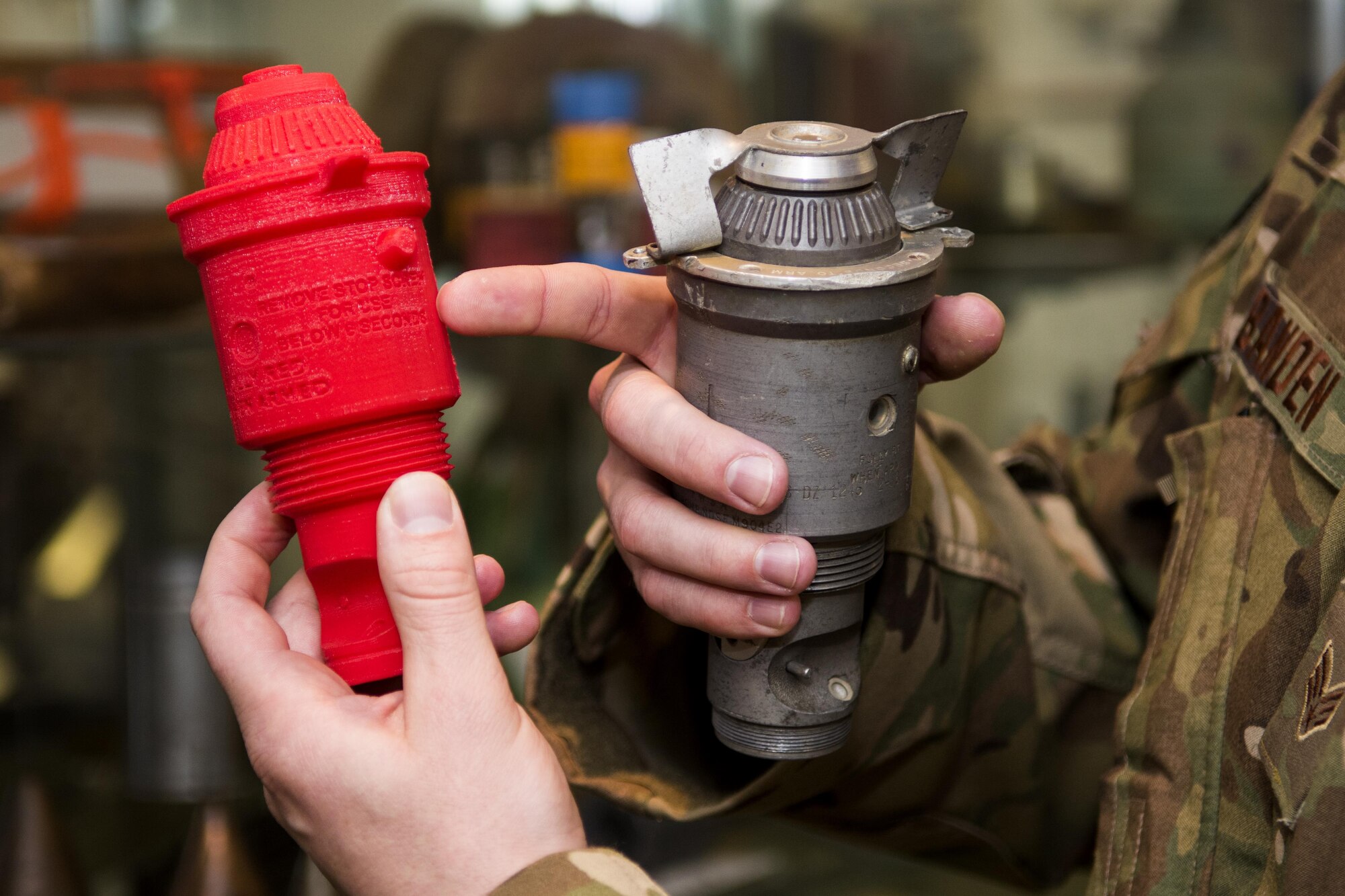 Senior Airman Nathanael Banden, 4th Civil Engineer Squadron explosive ordnance disposal technician, compares a M904 Bomb Nose Fuze to its 3-D printed counterpart, Dec. 14, 2016, at Seymour Johnson Air Force Base, North Carolina. With the ability to produce training aids using inexpensive plastic materials, EOD technicians can cut, shear, puncture or completely obliterate a training munition to fully complete an exercise without financial repercussions. (U.S. Air Force photo by Airman Shawna L. Keyes)