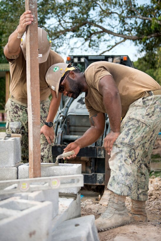 Navy Petty Officer 3rd Class Damon Lewis, right, and Petty Officer 2nd Class Jaime Buitrago level blocks for a five-stall bathroom they are building for the Sromo Primary School in Svay Rieng province, Cambodia, Jan. 9, 2017. Lewis and Buitrago are builders assigned to Naval Mobile Construction Battalion 5. Navy photo by Petty Officer 1st Class Benjamin A. Lewis
