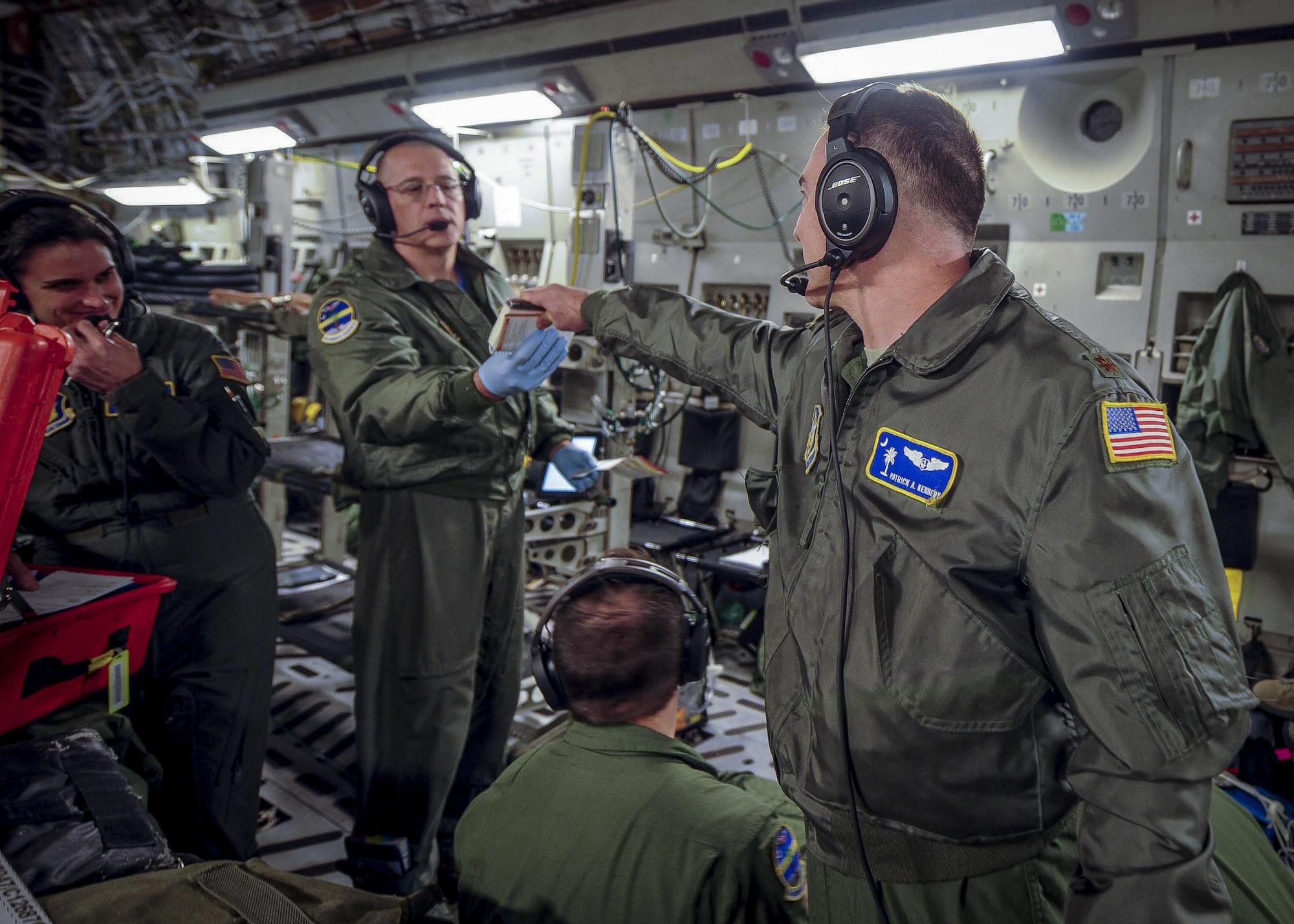 (From left) Maj. Patrick Kennedy, 315th Aeromedical Evacuation Squadron chief of standardizations and evaluations, hands a scenario card to Maj. Derek Stone, 315th AES, while conducting medical training Jan. 13, 2017, while on board a C-17 Globemaster III, bound for Ramstein Air Base, Germany. Each card contains various training emergencies for the medical professionals to overcome while in-flight. Airmen from the 315th AES are able to conduct medical training, while in conjunction with real-world operations. (U.S. Air Force photo by Senior Airman Tom Brading)