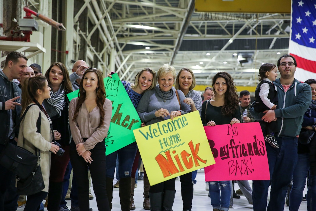 A group of friends and family members hold up signs while patiently awaiting the arrival of their loved ones aboard Marine Corps Air Station Cherry Point, Jan. 16, 2017. Marines assigned to Marine Attack Squadron 542 returned to MCAS Cherry Point after their deployment with the 31st Marine Expeditionary Unit. VMA-542 is assigned to Marine Aircraft Group 14, 2nd Marine Aircraft Wing. (U.S. Marine Corps photo by Lance Cpl. Cody Lemons/Released)