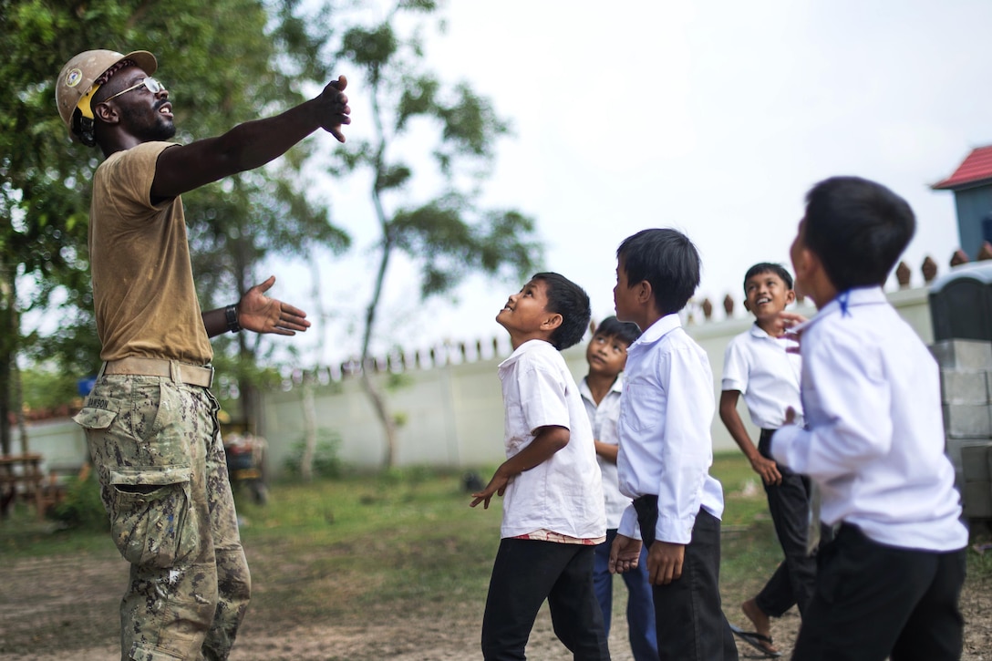 Navy Petty Officer 3rd Class Ashton Dawson, left, plays with students during a break from helping build a five-stall bathroom at Sromo Primary School in Svay Rieng province, Cambodia, Jan. 11, 2017. Dawson is a utilitiesman assigned to Naval Mobile Construction Battalion 5. Navy photo by Petty Officer 1st Class Benjamin A. Lewis