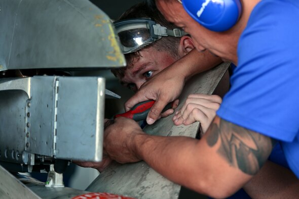 U.S. Air Force Senior Airman Brandon Atwell, left, and Staff Sgt. Paolo Santos, right, 20th Aircraft Maintenance Squadron weapons load crew member and load crew chief, close a forward fairing on a LAU-118 launcher at Shaw Air Force Base, S.C., Jan. 13, 2017. The fairing protects the umbilical cable which allows the aircraft to communicate with the missile. (U.S. Air Force photo by Airman 1st Class Kathryn R.C. Reaves)