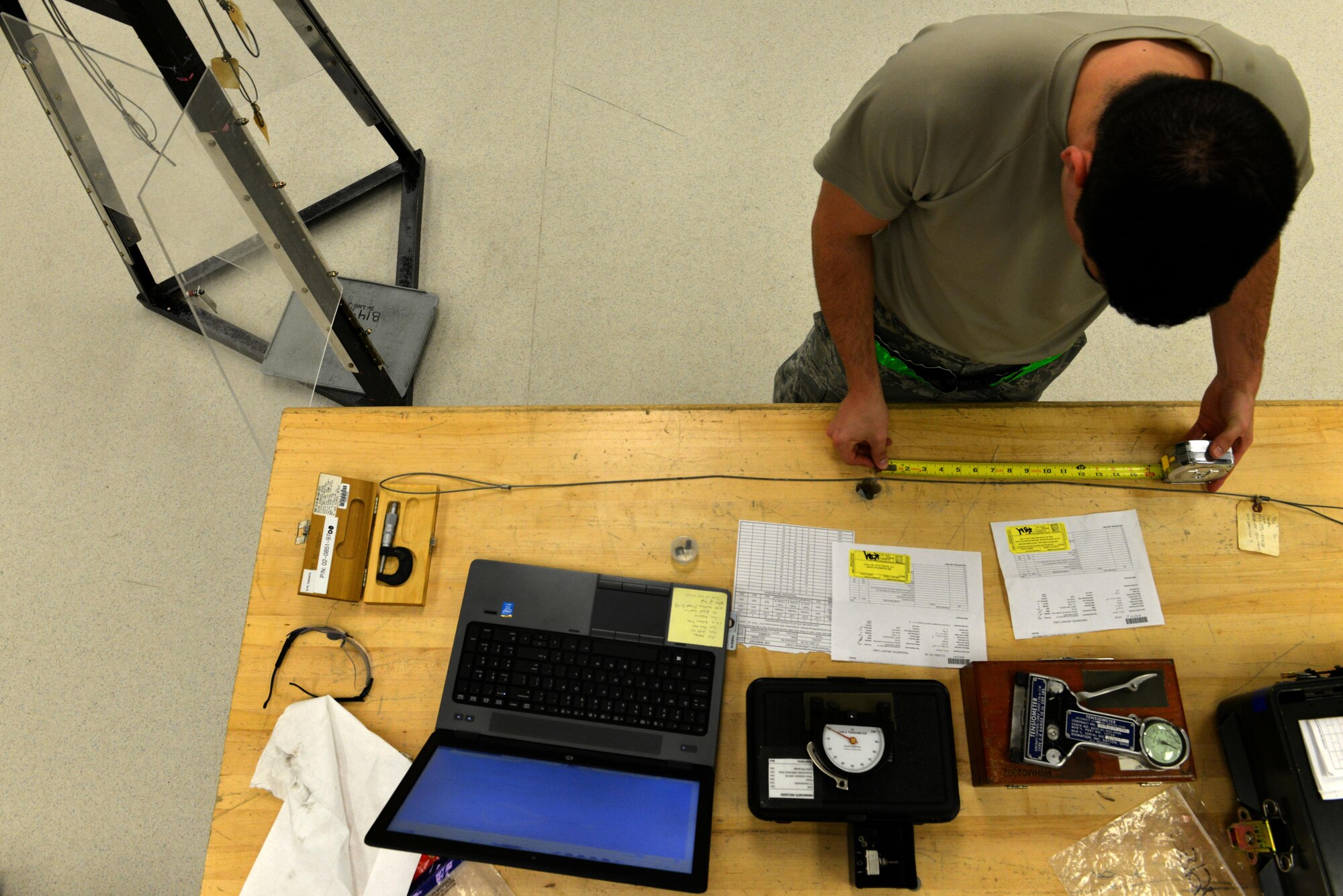 U.S. Air Force Airman 1st Class Jeremiah Zimmer, 20th Component Maintenance Squadron precision measurement equipment laboratory journeyman, measures a steel cord at Shaw Air Force Base, S.C., Dec. 22, 2016. Zimmer used the steel cords to suspend weights so that a tensiometer, which measures the tension of an object, could be calibrated. (U.S. Air Force photo by Airman 1st Class Destinee Sweeney)