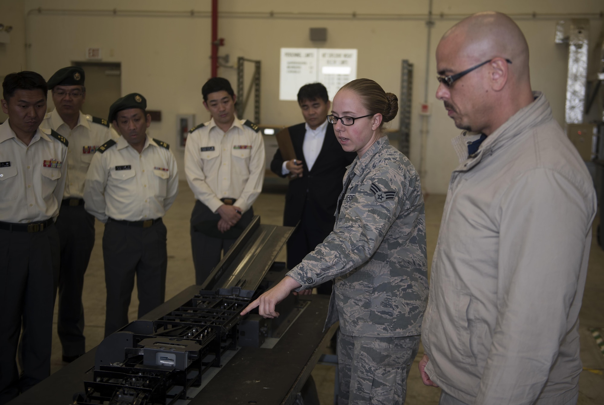 U.S. Air Force Senior Airman Mollye Voorhees, 18th Munitions Squadron conventional maintenance crew member, and Floyd Higa, 18th MUNS chief master labor contractor, show members of the Japan Ground Self-Defense Force different pieces of munitions equipment during a tour Jan. 11, 2017, at Kadena Air Base, Japan. These JGSDF members are training to become logistics officers and are touring U.S. munitions storage units to get an understanding of how they operate in an effort to stregthen ties between the U.S. and Japan. (U.S. Air Force photo by Airman 1st Class Corey Pettis/Released)