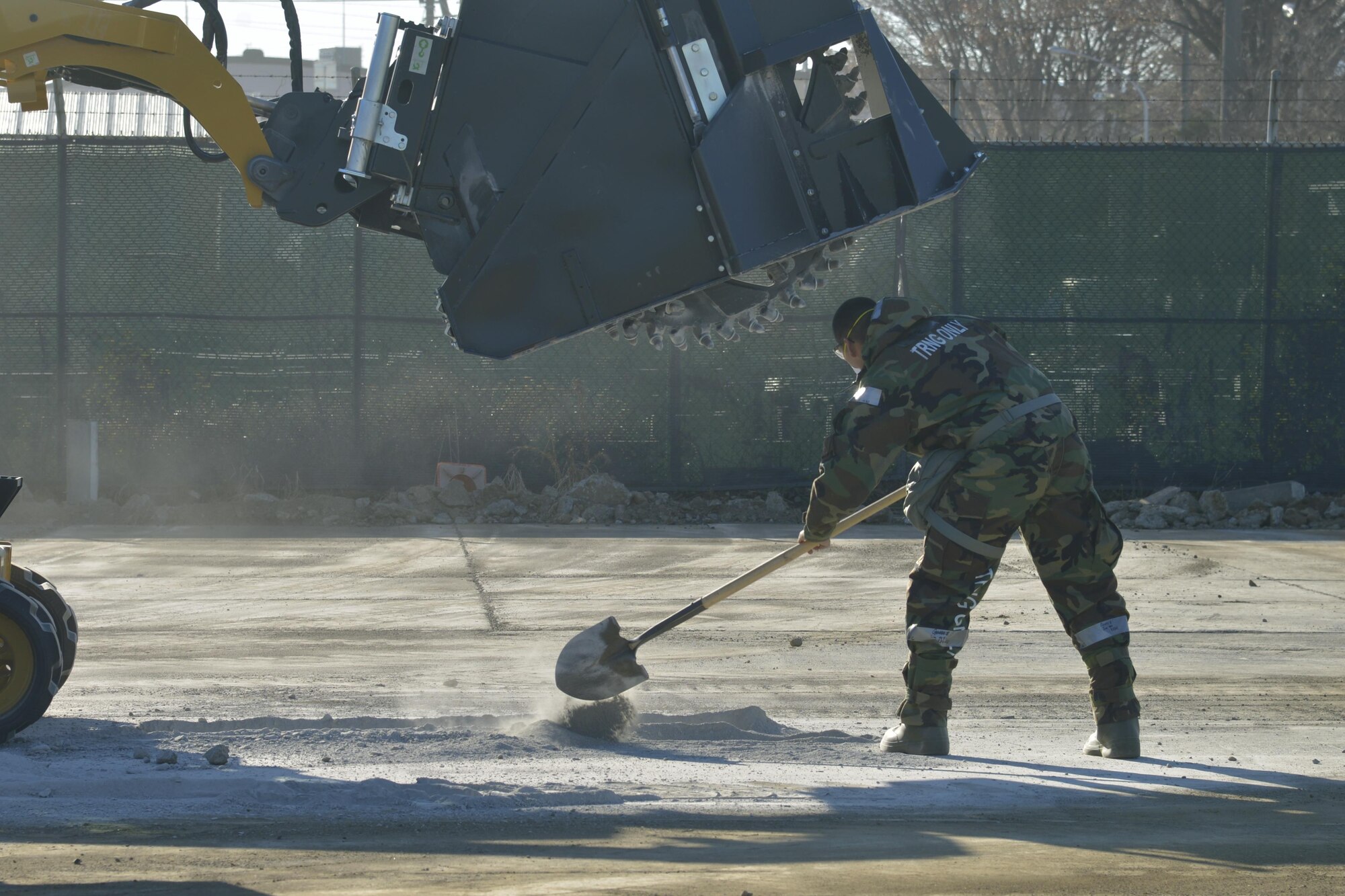 A member of the 374th Civil Engineer Squadron shovels dirt on the ground during a simulated crater repair scenario at Yokota Air Base, Japan, Jan. 12, 2017. In real world scenarios, Airmen will fill the crater with dirt to make it level with the ground to keep the flying mission running. (U.S. Air Force photo by Staff Sgt. David Owsianka)