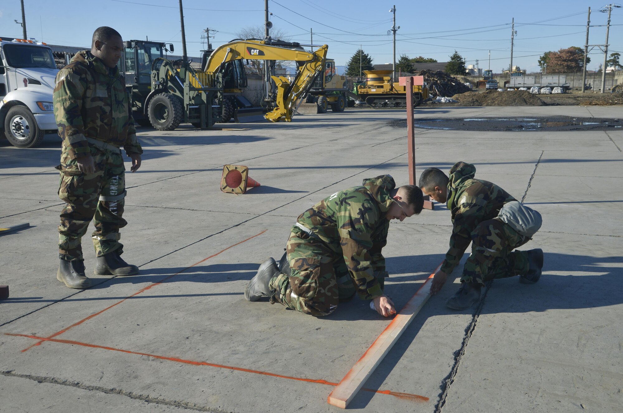 Members of the 374th Civil Engineer Squadron create lines for others to cut the cement during a simulated crater repair scenario at Yokota Air Base, Japan, Jan. 12, 2017. The training provides Airmen with the opportunity to practice and hone their skillset for potential real world scenarios. (U.S. Air Force photo by Staff Sgt. David Owsianka)