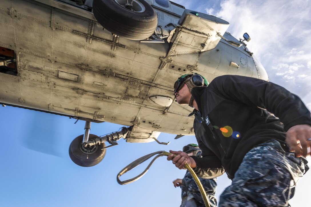 Petty Officer 2nd Class Jason Lee attaches a torpedo recovery device to an MH-60S Seahawk helicopter during range operations at San Clemente Island, Calif., Jan. 11, 2017. Navy photo by Petty Officer 2nd Class Chad M. Butler