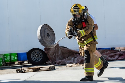 A 380th Expeditionary Civil Engineering Squadron firefighter throws a hose during a timed firefighter confidence course at an undisclosed location in Southwest Asia, Jan. 16, 2017. Wearing up to 75 pounds of equipment, participants completed nine stages during the course including a ladder climb, hose drag, sled pull, hose throw, equipment carry, forcible entry, hotel pack, equipment hoisting and rescue. (U.S. Air Force photo/Senior Airman Tyler Woodward)
