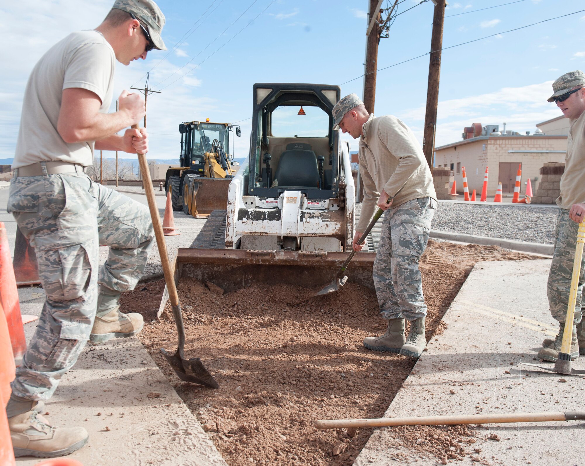 Staff Sgt. John Hoyt and Senior Airman Jordan Lechner, Pavement and Equipment craftsmen, assigned to the 49th Civil Engineer Squadron, shovel soil into a loader at Holloman Air Force Base, N.M., January 17, 2017. In order for asphalt to be placed onto the surface, the soil underneath it must be as smooth as possible. A utility break occurred under the roadway causing for the 49th CES to quickly respond and fix the problem. (U.S. Air Force photo by Airman Ilyana A. Escalona)