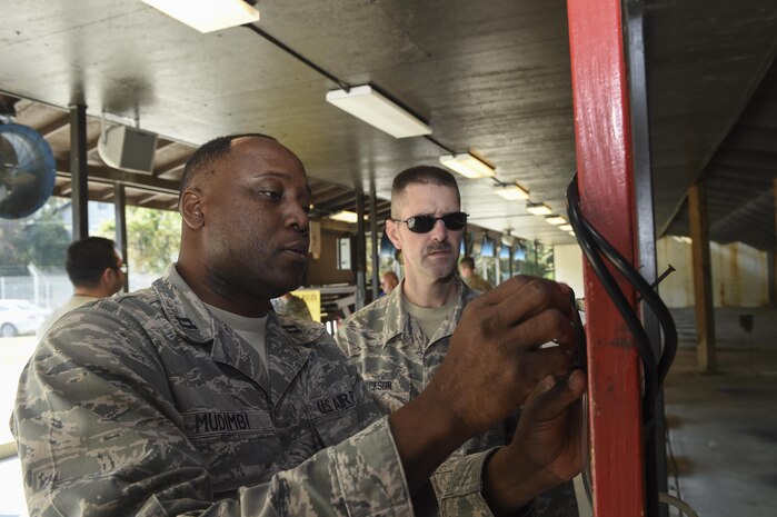 Capt. Patrick Mudimbi, 711th Human Performance Wing, Wright-Patterson Air Force Base, Ohio, chemical health consultant, left, and Tech. Sgt. Jerimiah Jackson, 711th HPW Force Health Protection NCO in charge, right, set up scanners to analyze the chemicals expended from weapons being fired at the Combat Arms Training and Maintenance firing range at Joint Base Charleston, South Carolina, Nov. 17, 2016. The focus of their research is to determine if expended fumes are being properly ventilated.