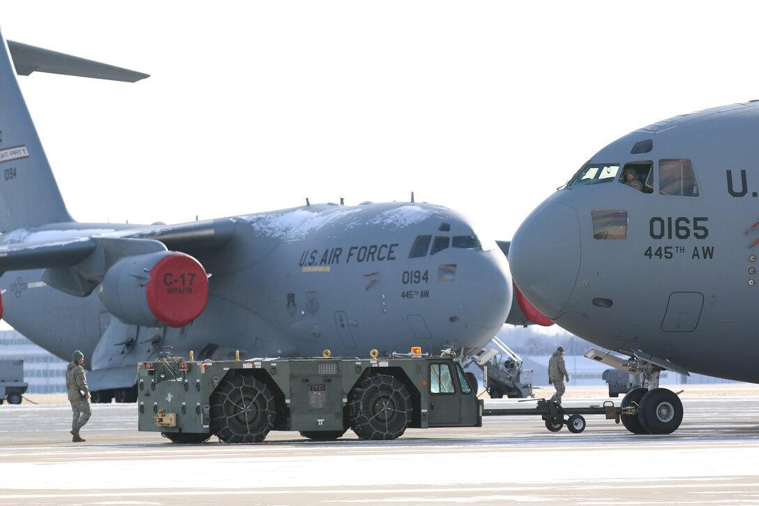 Airmen from the 445th Aircraft Maintenance Squadron work together to tow a C-17 Globemaster III out of a hangar and to the ramp during the January 8, 2017 unit training assembly. The aircraft is standing by to fly its next mission. (U.S. Air Force photo /Tech. Sgt. Patrick O’Reilly)