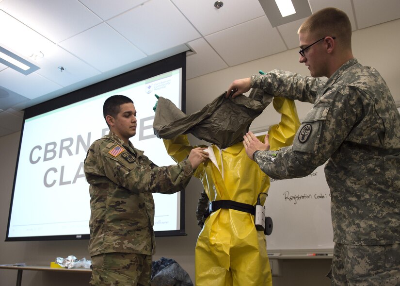 U.S. Army Staff Sgt. Jonathan Chambers, left, U.S. Army Element South Troop Command Alpha Company emergency response team senior enlisted leader, and Army Pfc. Lewis Warren, U.S. AESTC Bravo Company detection team leader, instruct a classroom of military medical personnel on how to properly put on personal protective equipment during a chemical, biological, radiological and nuclear defense class at the Fort Belvoir Community Hospital in Fort Belvoir, Va., Jan. 13, 2017. The CBRN training portion of the day allowed instructors to answer any questions, give a thorough walkthrough of how to put on the equipment and hand out any additional equipment needed in preparation for a worst case scenario. (U.S. Air Force photo by Senior Airman Philip Bryant)