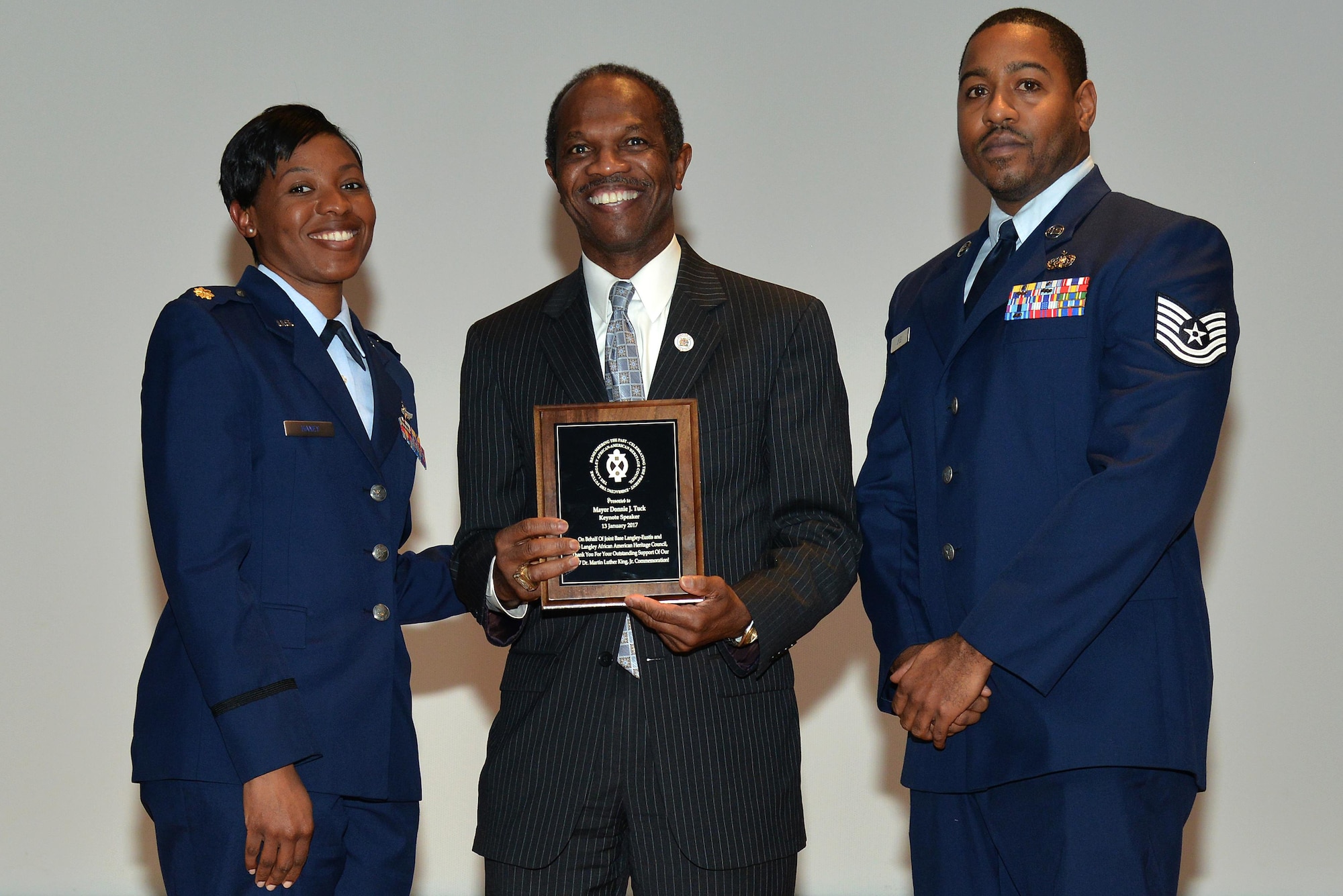 U.S. Air Force Maj. Ebony Haney, Air Combat Command Communication Support Squadron flight commander, and U.S. Air Force Tech. Sgt. Touré Lyle, ACC Air Operations Squadron communications NCO in charge, present the Honorable Donnie Tuck, Hampton, Va., Mayor, with a plaque during the Martin Luther King Jr. event at Joint Base Langley-Eustis, Va., Jan. 13, 2017. Tuck was a guest speaker during the event where he gave a speech about the importance of Dr. Martin Luther King Jr.’s accomplishments and the reason this event is held.(U.S. Air Force photo by Airman 1st Class Tristan Biese)