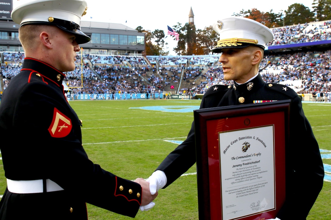 U.S. Marine Corps Lance Cpl. Jeremy Fredrichsdorf (left) receives the Commandant of the Marine Corps Trophy from Brig. Gen. Thomas A. Gorry, Commandant of the Dwight D. Eisenhower School for National Security and Resource Strategy, Nov. 19, 2016, at the University of North Carolina at Chapel Hill. Fredrichsdorf performed as the top candidate out of a class of more than 200 at the U.S. Marine Corps Officer Candidate School based on evaluations on academic performance, physical fitness and leadership.  (U.S. Marine Corps photo by Sgt. Antonio J. Rubio/Released)