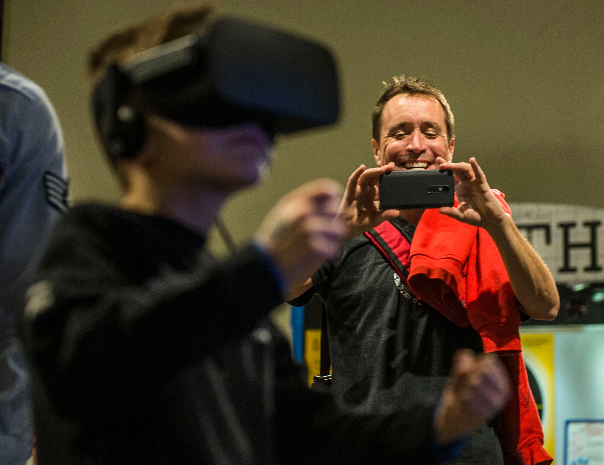 A father takes a picture of his son while he has a virtual reality experience at the Air Force booth. (U.S. Air Force photo by Staff Sgt. Jodi Martinez)