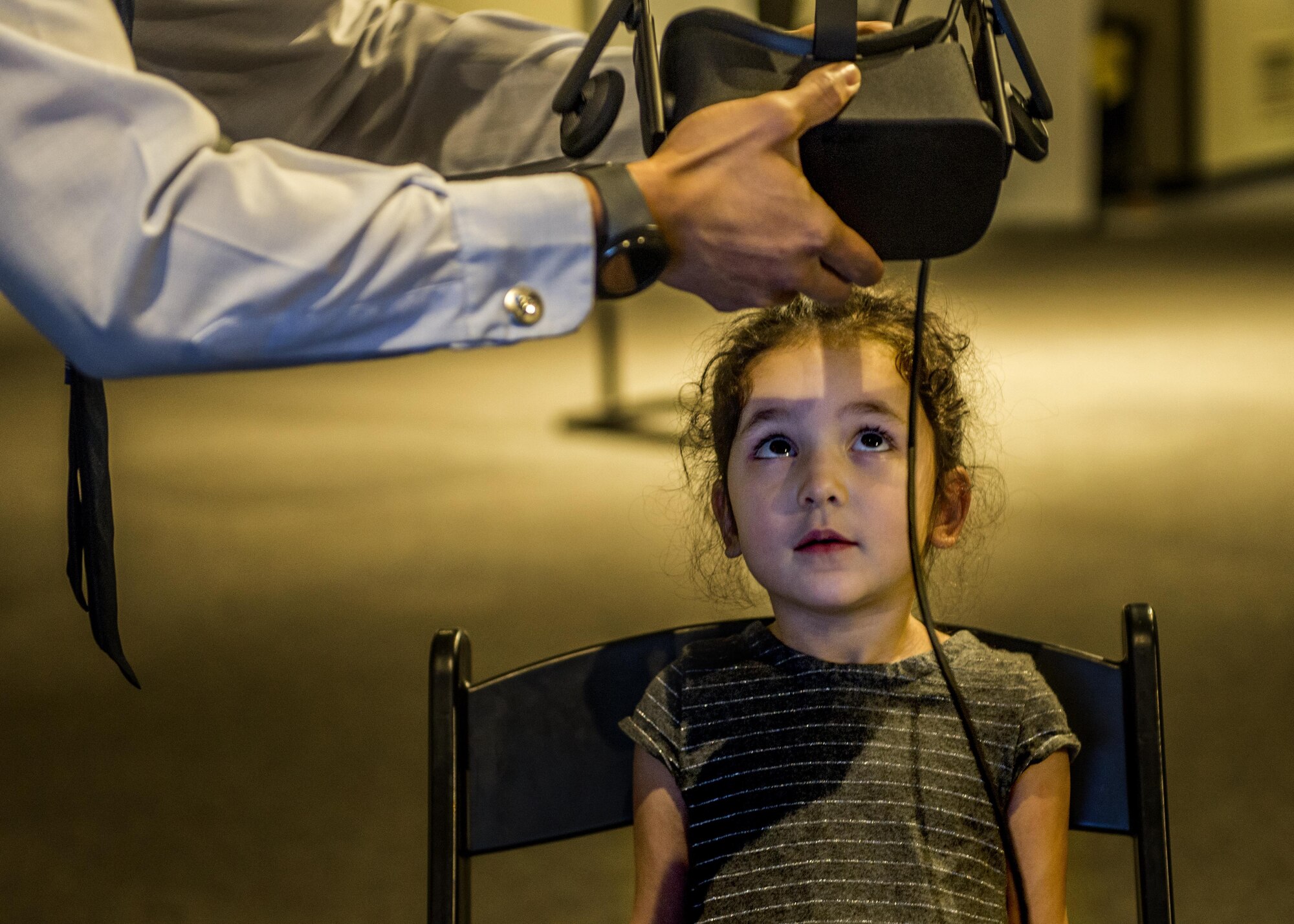 Staff Sgt. Charles Quinsay, helps a visitor adjust the virtual reality headset. (U.S. Air Force photo by Staff Sgt. Jodi Martinez)