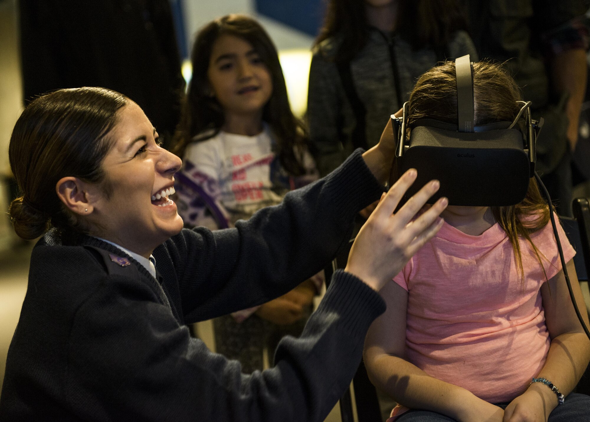Staff Sgt. Merissa Hunnicut, 345th Recruiting Squadron recruiter, laughs as she helps a visitor put on the virtual reality headset. (U.S. Air Force photo by Staff Sgt. Jodi Martinez)