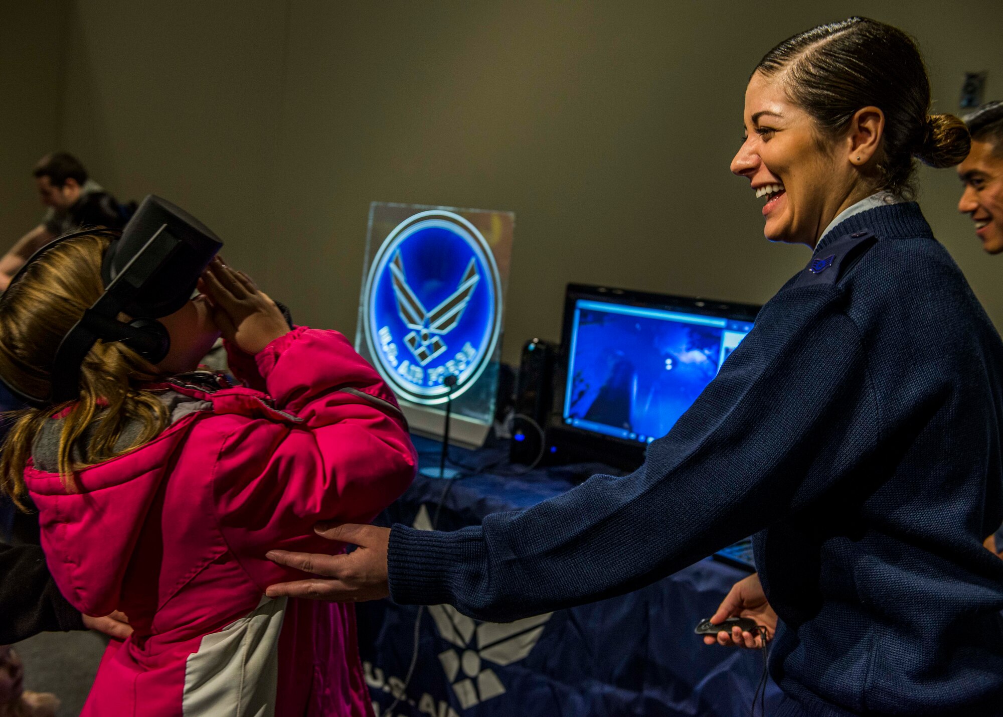 Staff Sgt. Merissa Hunnicut, 345th Recruiting Squadron recruiter, laughs while she helps a young girl use the virtual reality during the event. (U.S. Air Force photo by Staff Sgt. Jodi Martinez)