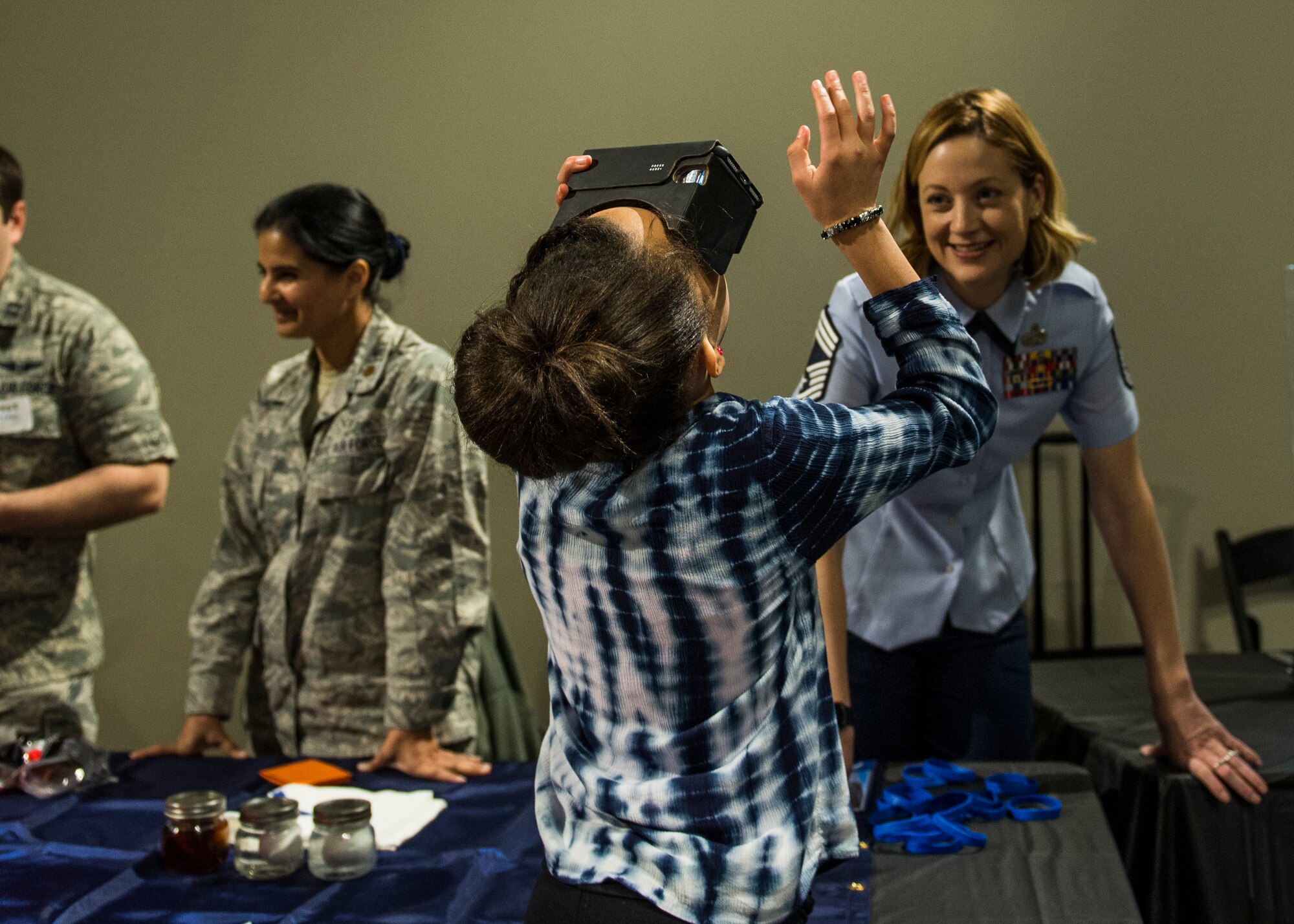A girl uses Google cardboard virtual reality to see what it’s like to jump out of a plane.  (U.S. Air Force photo by Staff Sgt. Jodi Martinez)