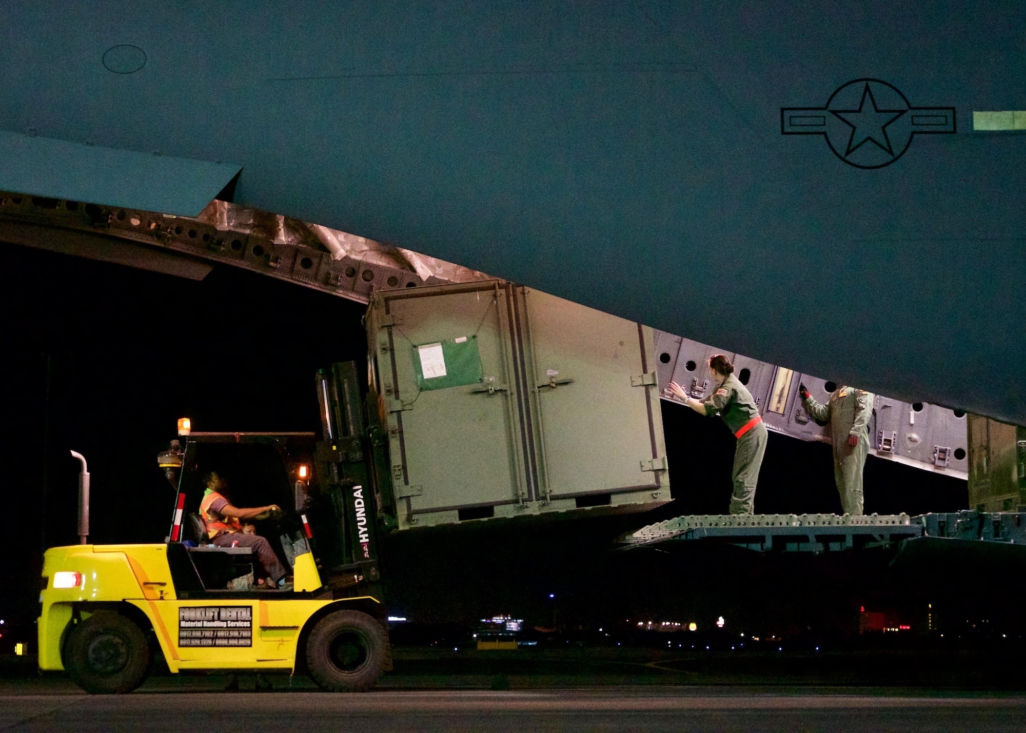 U.S. Air Force Master Sgt. Kerrie Morris, loadmaster, guides a Filipino forklift operator while unloading a C-17 Globemaster III after arriving at Clark Air Base, Philippines, Jan. 14, 2017. The aircraft transported a team of U.S. Airmen and Soldiers and a ground-based commercial satellite imagery system known as Eagle Vision. While in the Philippines, the U.S. servicemembers will share experiences with their Philippine Air Force allies in using Eagle Vision and satellite imagery as a tool for enhancing their combined Humanitarian Assistance and Disaster Relief capabilities. (U.S. Air Force photo by Tech. Sgt. James Stewart/Released)