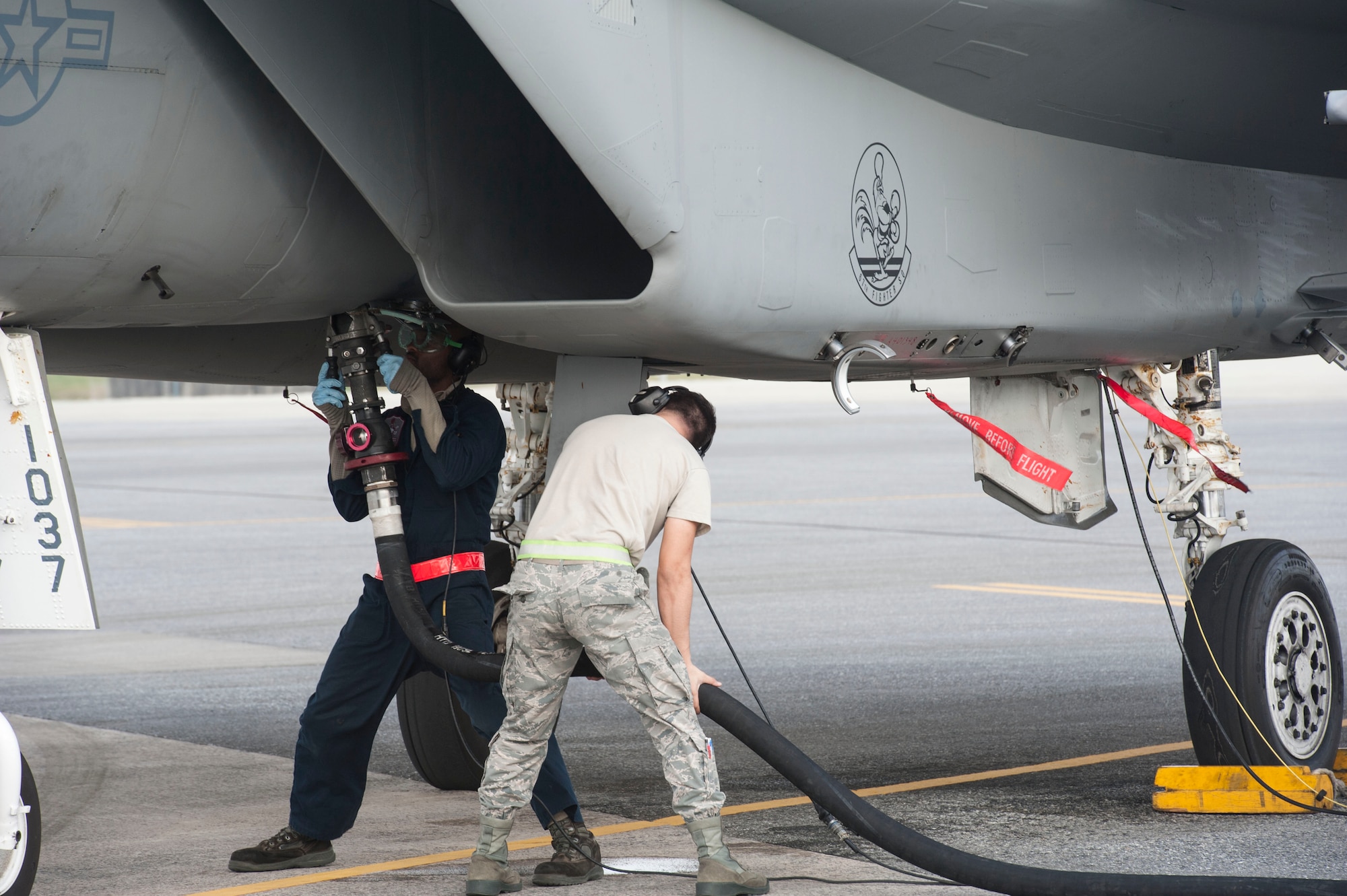 U.S. Air Force Senior Airman Marcus Leonard, left, 18th Aircraft Maintenance Squadron crew chief, and Airman 1st Class Moises Leos, right, 18th Logistics Readiness Squadron fuels distribution operator, refuel an F-15 Eagle during surge operations Jan. 11, 2017, at Kadena Air Base, Japan. During this particular surge, the 67th Fighter Squadron exceeded their sortie goals for the given timeframe. (U.S. Air Force photo by Senior Airman Lynette M. Rolen/Released)