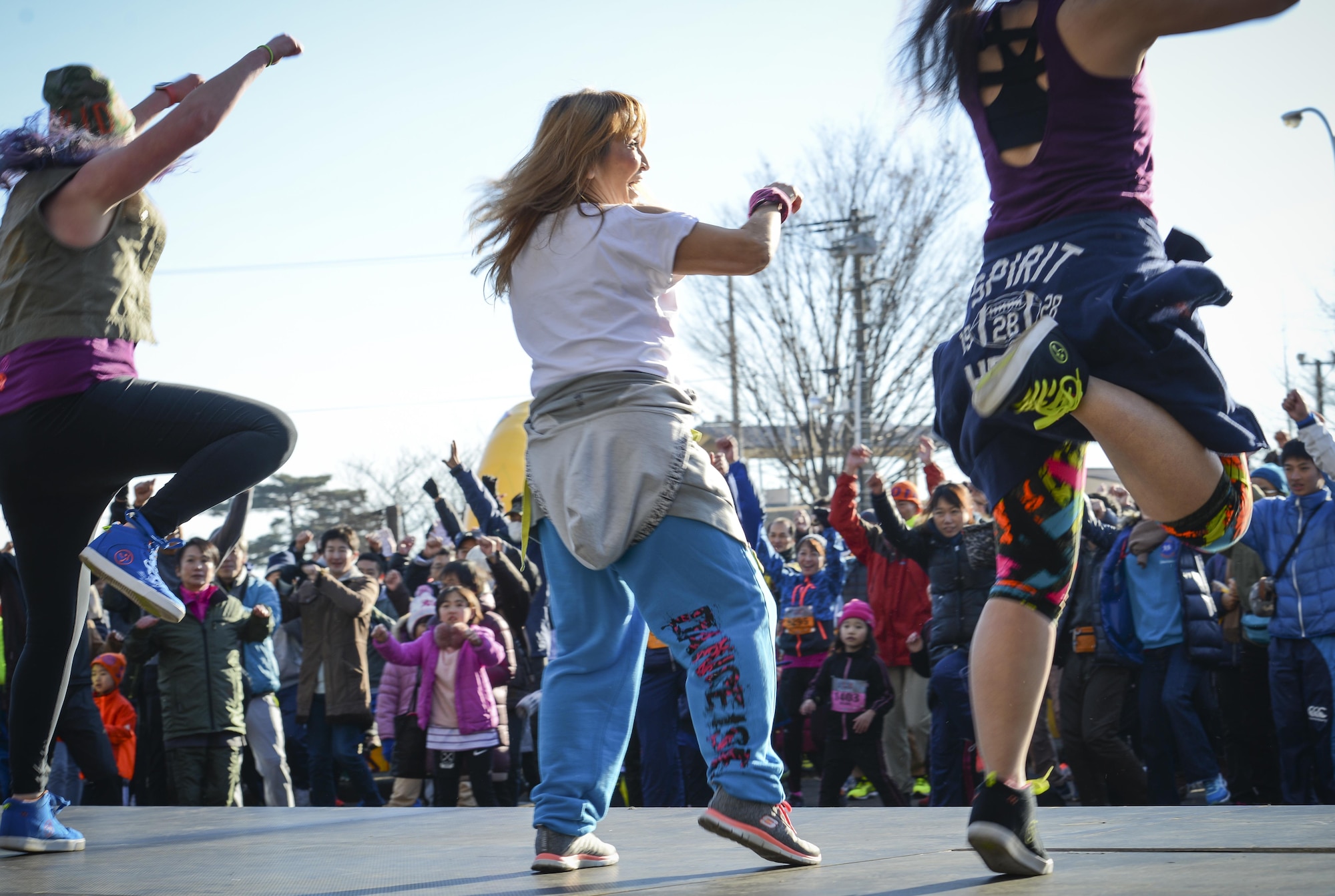 Ally Wahburn, left, Ako Sawada and Mako Ishida Entzminger, 374th FSS Samurai Fitness Center Zumba instructors lead the crowd in a warmup during the 36th Annual Yokota Striders Frostbite Race at Yokota Air Base, Japan, Jan. 15, 2017. Approximately 12,000 runners and guests attended the race this year, promoting friendship and physical fitness. (U.S. Air Force photo by Senior Airman Baker)