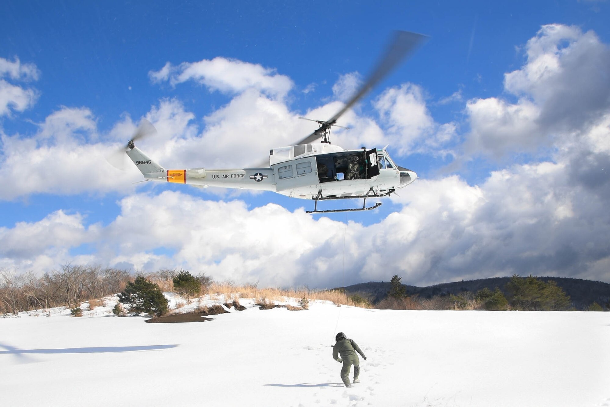 Lt. Col. Valerie Johnson, 374th Medical Group aerospace medicine chief, walks towards a UH-1N Iroquois to be lifted into the aircraft at a drop zone near Mt. Fuji, Japan, Jan. 13, 2017. The aircrew completed hoist insertion and extraction from the helicopter from 25-35 feet above the ground. (U.S. Air Force photo by Staff Sgt. David Owsianka)