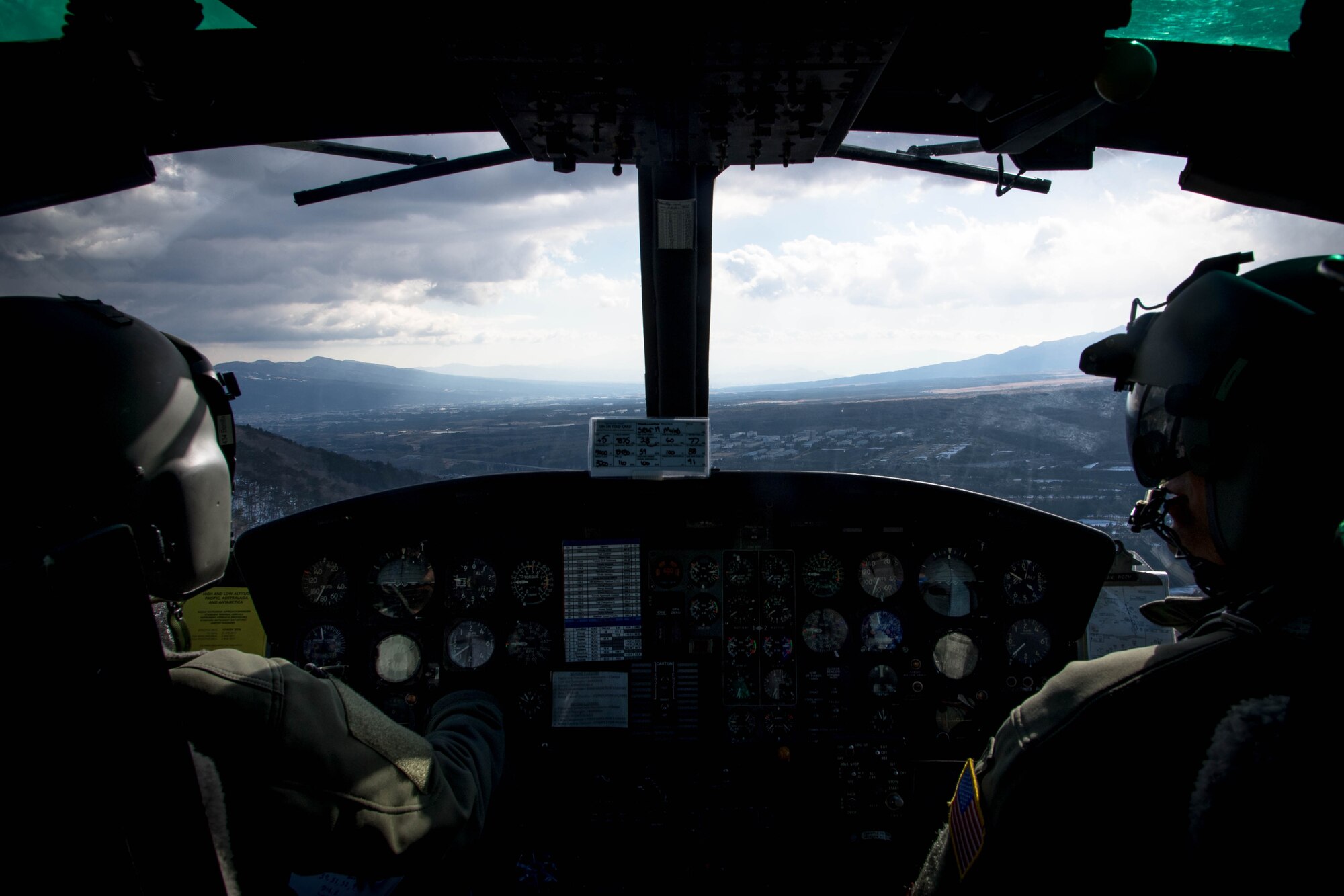 Capt. Johnathan Bonilla, 459th Airlift Squadron standards and evaluations chief, left, and Capt. Vincente Vasquez, 459 AS aircraft commander, fly over a drop zone near Mt. Fuji, Japan, Jan. 13, 2017. Having the hoist allows the 459 AS to conduct rescue missions in small, tight areas throughout the Kanto Plains. (U.S. Air Force photo by Staff Sgt. David Owsianka)