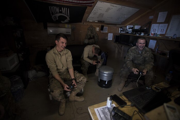 Senior Airman Domynic Panto and Tech. Sgt. Bob Kaster, 455th Expeditionary Aircraft Maintenance Squadron C-130 Compass Call Aircraft Maintenance Unit communications navigations and mission systems technicians, and Airman 1st Class Mitchell Dillon, 455th EAMXS C-130 AMU electronic warfare combat systems technician, play video games at Bagram Airfield, Afghanistan Jan. 12, 2017. When they’re not working out on the flightline, members of the AMU play sports or video games and work out together. (U.S. Air Force photo by Staff Sgt. Katherine Spessa)