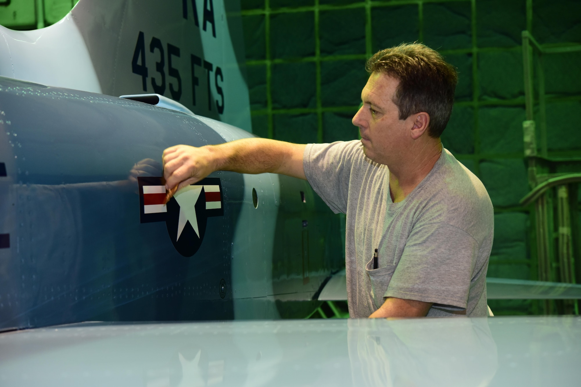 Neil Orlowski, a Corrosion Control Specialist in the 12th Maintenance Group, applies a decal to a T-38C Talon at Joint Base San Antonio-Randolph, Texas, Jan. 13, 2017.  Members of the corrosion control shop are changing the plane’s color scheme from two-tone gray to heritage blue, a scheme that was used by the 435th Fighter Training Squadron 40 years ago, ahead of a reunion of pilots that trained for fighter fundamentals after Jan. 1, 1977. (U.S. Air Force photo/Randy Martin) 