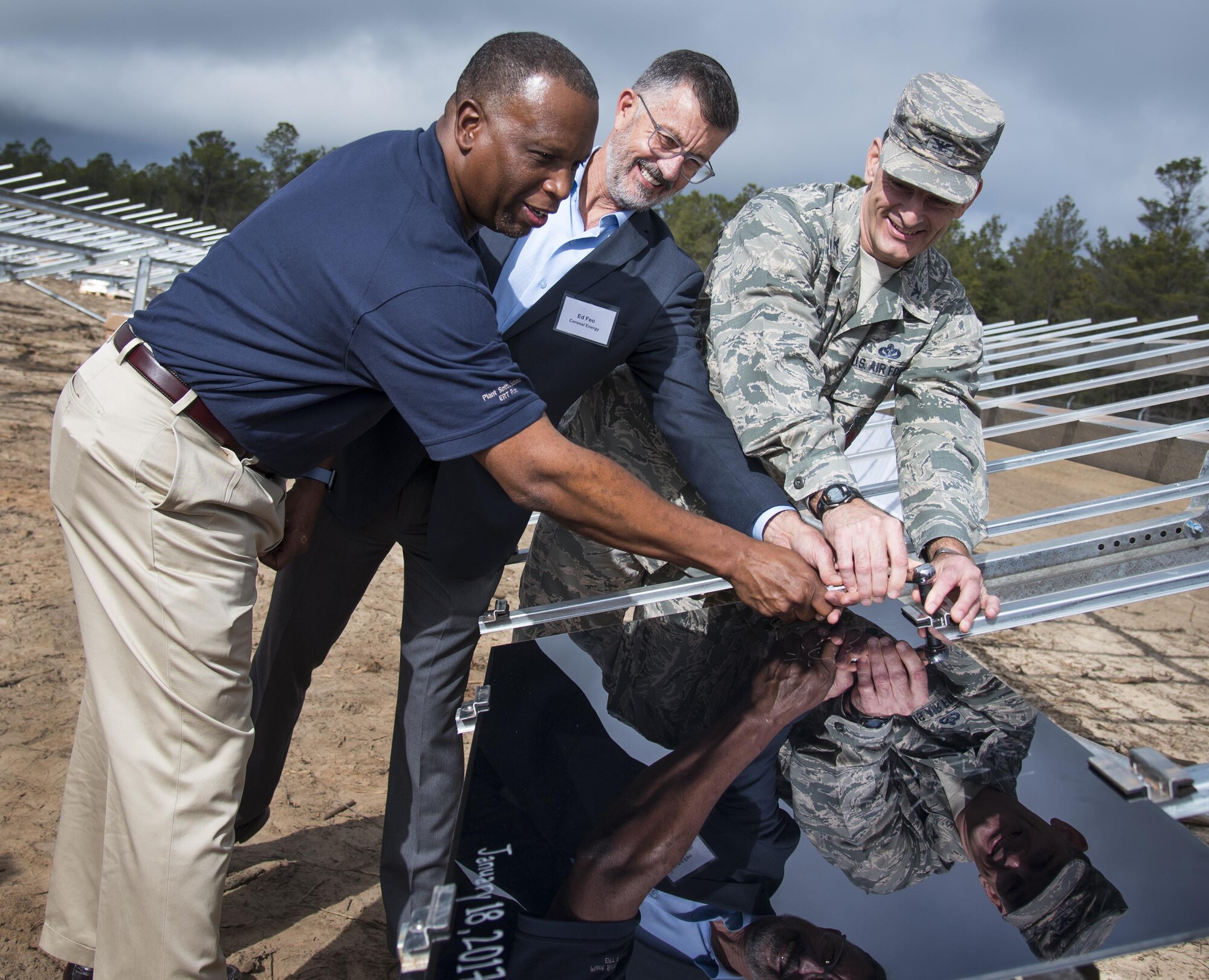 Mike Burrows, Gulf Power, Ed Feo, Coronal Development Services and Col. Craig Johnson, 96th Test Wing, simultaneously turn the wrench to install a solar panel at a small ceremony Jan. 18 at Eglin Air Force Base, Fla.  Leaders from the three project partners installed the first of the eventual 375,000 solar panels that will be located on the 240-acre site.  (U.S. Air Force photo/Samuel King Jr.)
