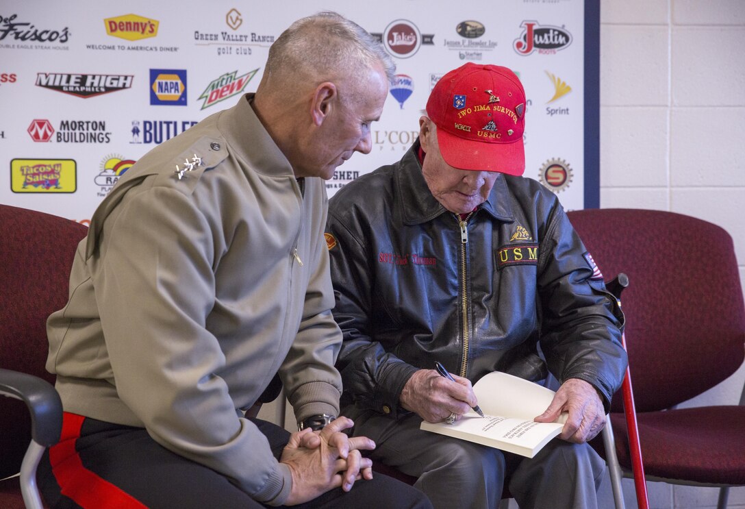 Lt. Gen. Rex C. McMillian, commander of Marine Forces Reserve and Marine Forces North, sits with World War II and Iwo Jima veteran Jack Thurman at the National Western Stock Show in Denver, Jan. 17, 2017. Thurman, a member of the original Marine Corps Raiders, autographs a copy of a book he wrote that chronicles his time in the Marine Corps. The NWSS honored veterans to show their dedication to the military and to bring attention to the 100th anniversary of the Marine Corps Reserves. (U.S. Marine Corps photo by Lance Cpl. Dallas Johnson/Released)