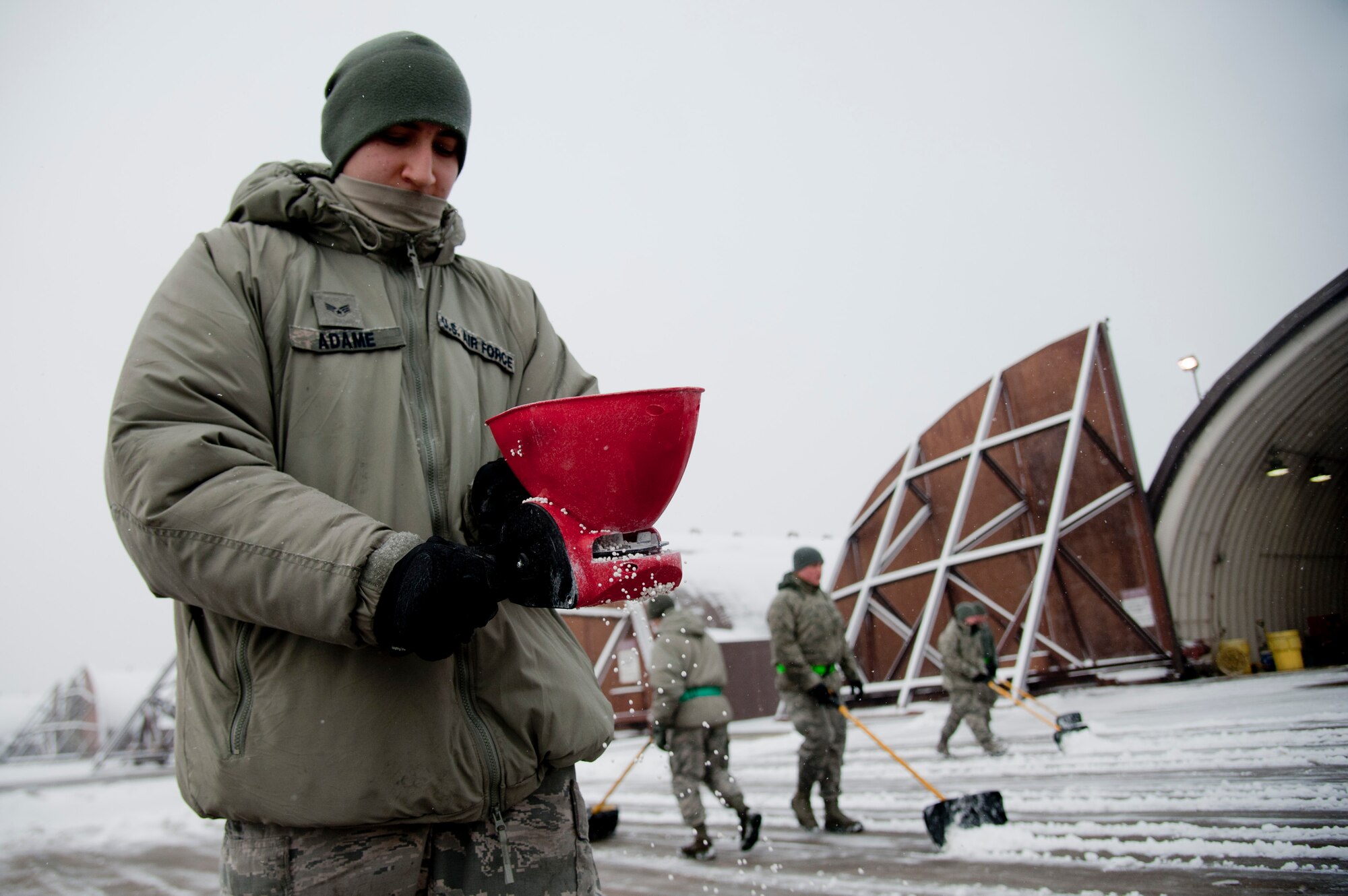 U.S. Air Force Senior Airman Mario Adame, 25th Aircraft Maintenance Unit electrical environmental systems journeymen, spreads salt to melt ice in front of an aircraft hangar on Osan Air Base, Republic of Korea, Jan. 20, 2017. The 25th AMU removed snow in front of their hangers to keep the A-10 Thunderbolt II “ready to fight tonight”. (U.S. Air Force photo by Staff Sgt. Jonathan Steffen)