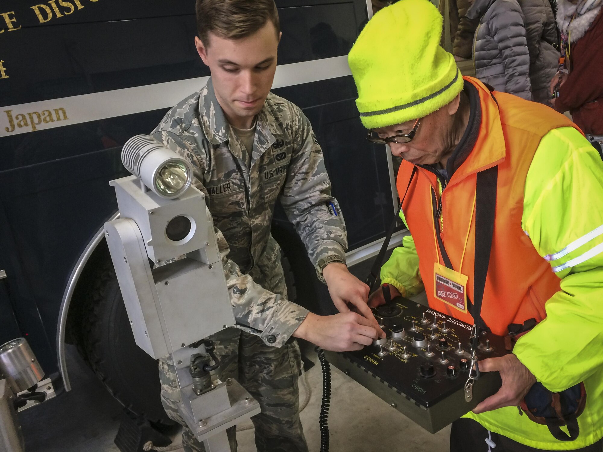 U.S. Air Force Airman 1st Class Christopher Waller, an explosive ordnance disposal apprentice with the 35th Civil Engineer Squadron, shows a Japanese man how to oper-ate the unit’s bomb disposal robot during a community relations tour at Misawa Air Base, Japan, Jan. 20, 2017. The robot helps EOD Airmen at home and downrange dis-pose of bombs without putting human life at risk. The robots, considered unmanned ground vehicles, enter areas inaccessible or too dangerous for people, while providing state-of-the-art technology in reconnaissance. (U.S. Air Force photo by Staff Sgt. Ben-jamin W. Stratton)