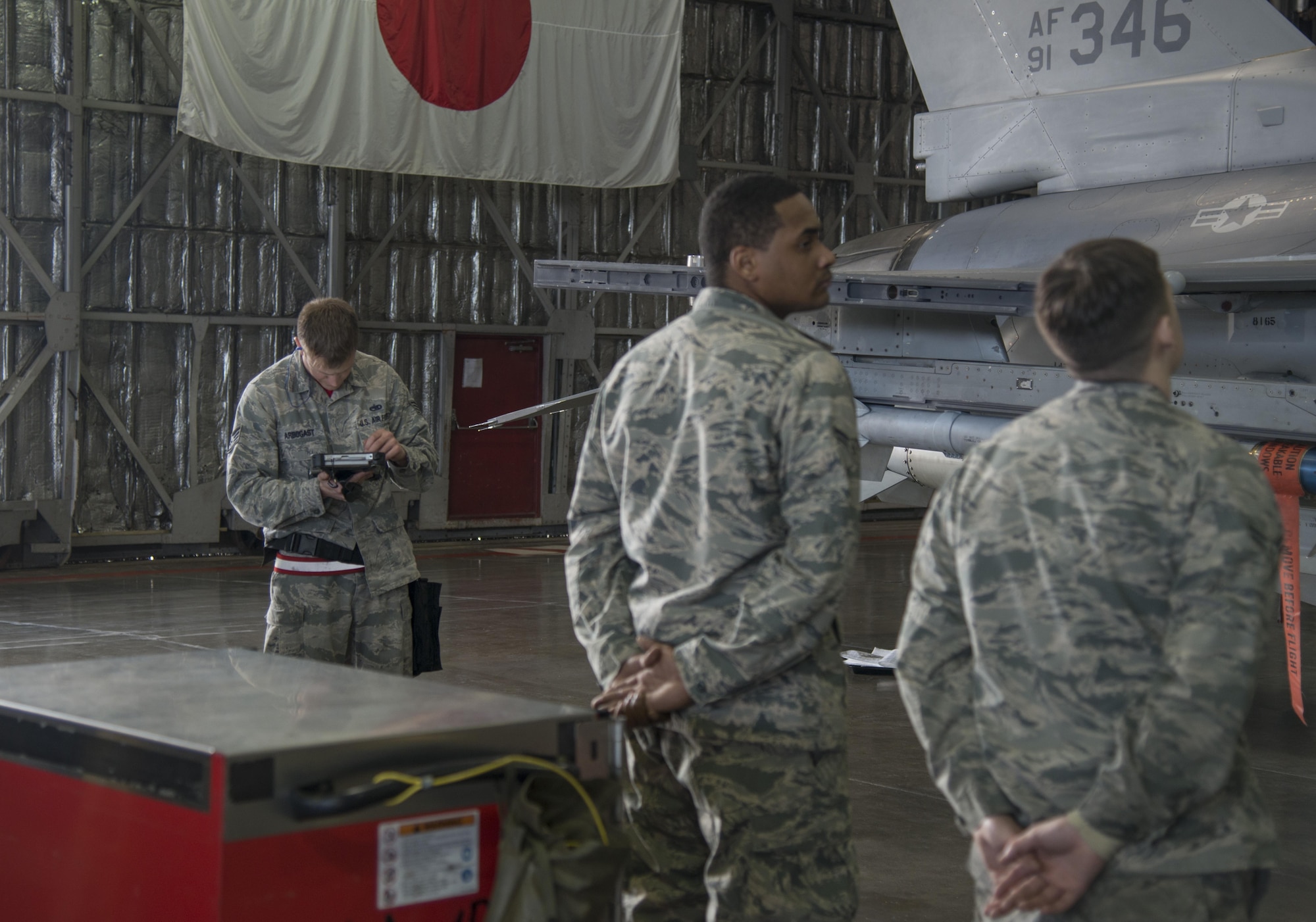 U.S. Air Force Staff Sgt. Brian Arborgast, the team chief with the 13th Aircraft Maintenance Unit load crew 10, checks a handheld technical order as his team, Airman 1st Class Hassan Cole, center, and A1C Korey Giffin-Pope, both load crew 10 team members with the 13th Aircraft Maintenance Squadron, during the annual load crew competition at Misawa Air Base, Japan, Jan. 20, 2017. During the competition, load crew team 3 and 10 raced against the clock, and each other, to arm an F-16 Fighting Falcon with one AIM-9 Sidewinder a short-range air-to-air missile, one AIM-120 advanced medium range air-to-air missile, an AGM-88 High-Speed Anti-Radiation Missile and a Joint Direct Attack Munition GBU 31 (v) 3/B. (U.S. Air Force photo by Senior Airman Brittany A. Chase)
