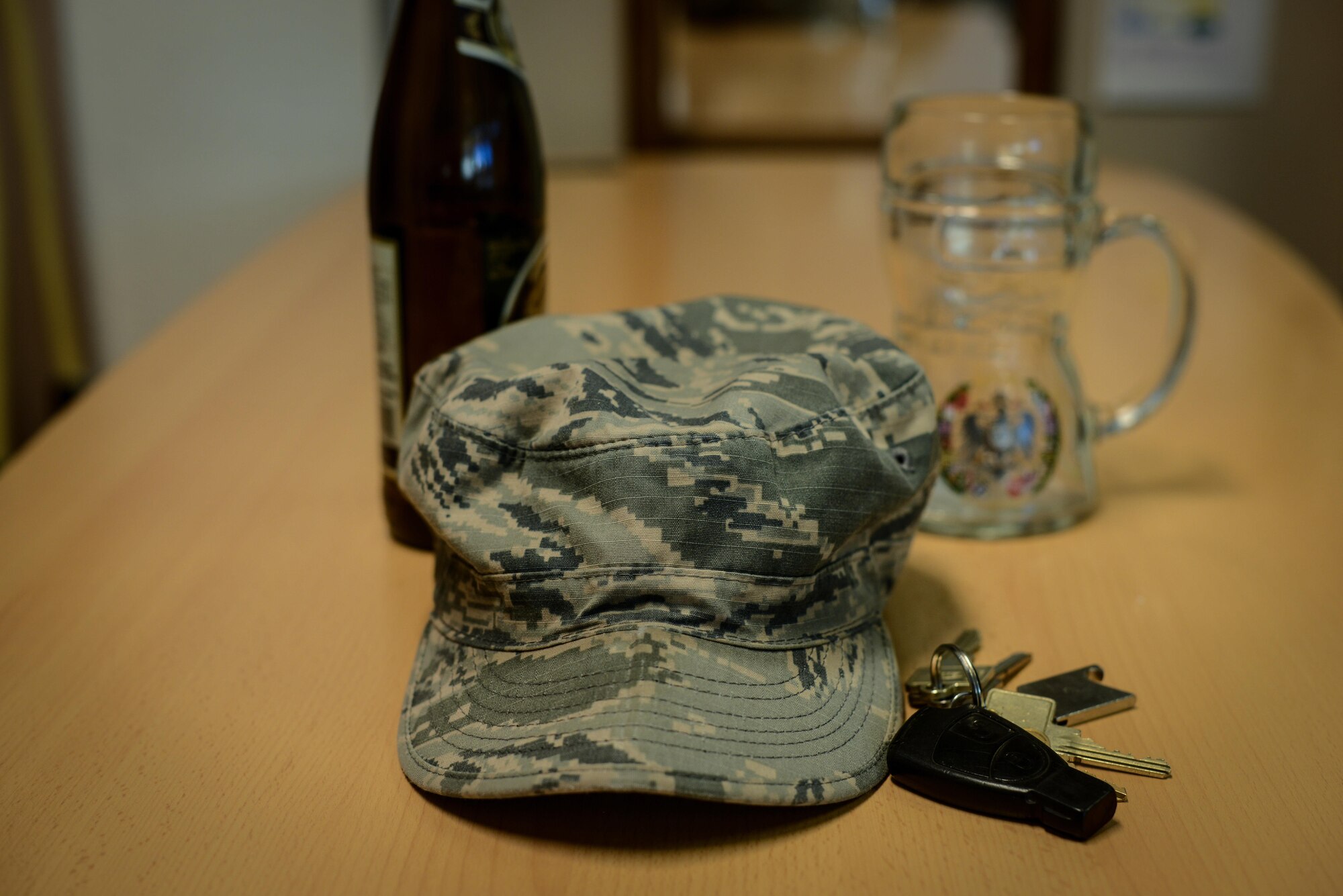 A crumpled Airman Battle Uniform cap lies on a table next to a key set, beer bottle, and beer mug at Ramstein Air Base, Germany, Jan. 20, 2017. The Airman Against Drunk Driving program is available at many Air Force Bases and aims to prevent cases of DUI among Airmen. (U.S. Force photo by Airman 1st Class Joshua Magbanua)